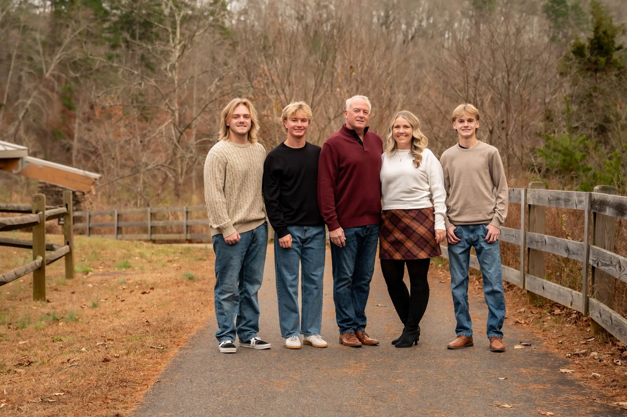 Family walking together along a wooden fence path during autumn.