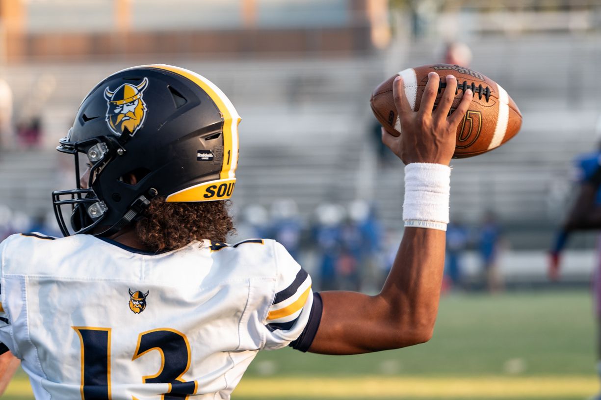 Football player in navy and gold uniforms running plays during a game in Mooresville, NC