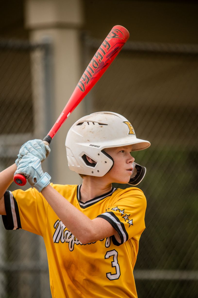 Baseball player in yellow jersey swinging bat during game action sequence.