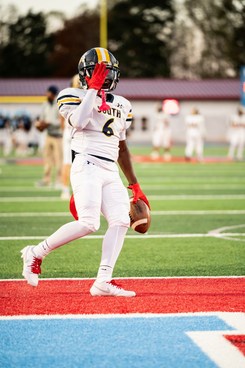Football player in white uniform holds ball in endzone during game.