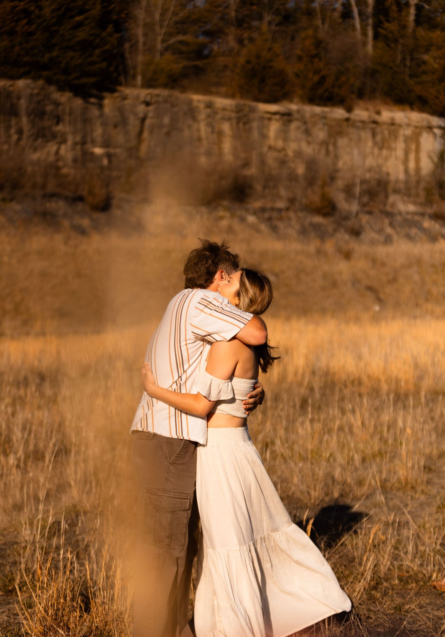 Couple embraces in a sun-drenched field with warm autumn colors.