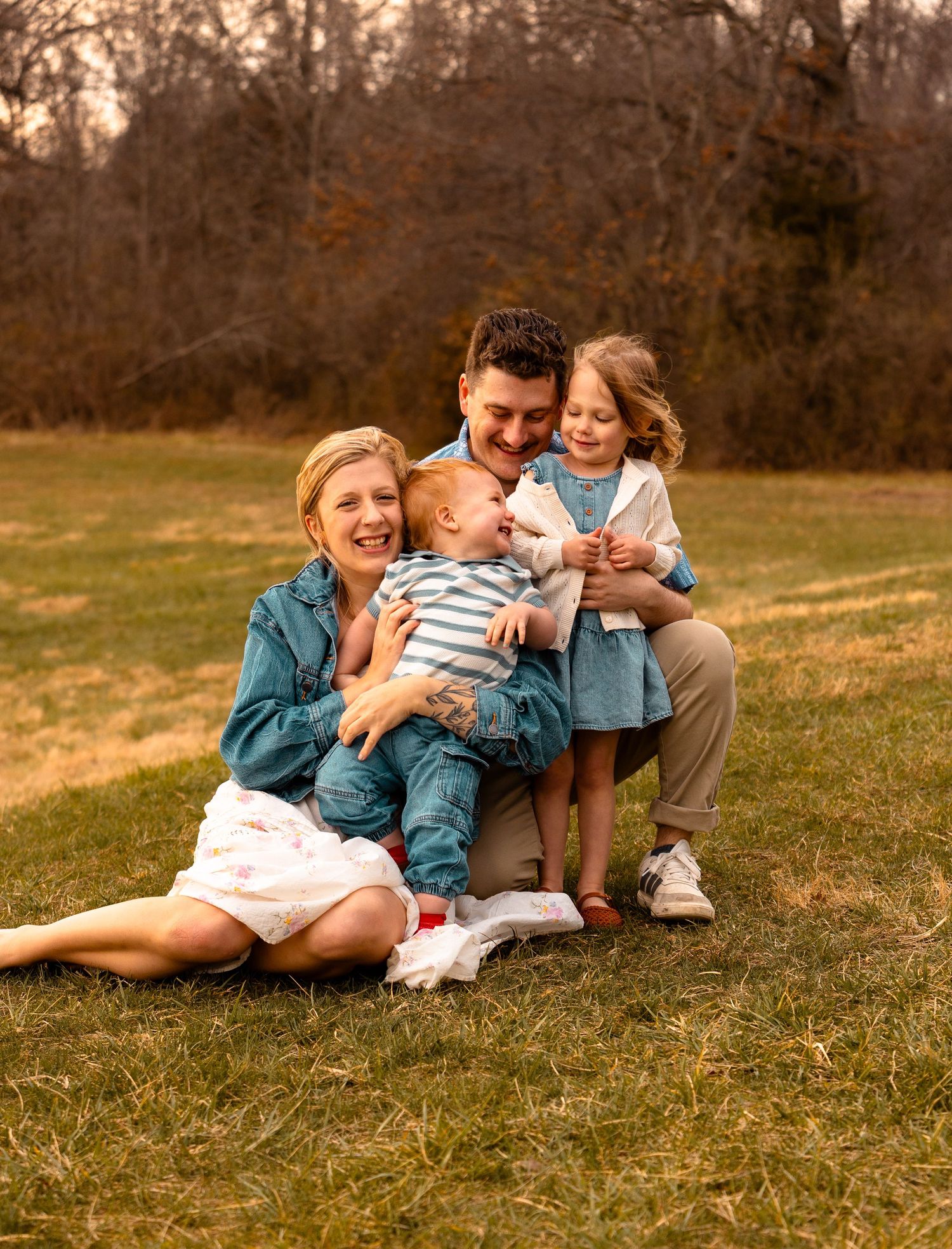 Happy family sitting together on grass during sunset in warm autumn colors.