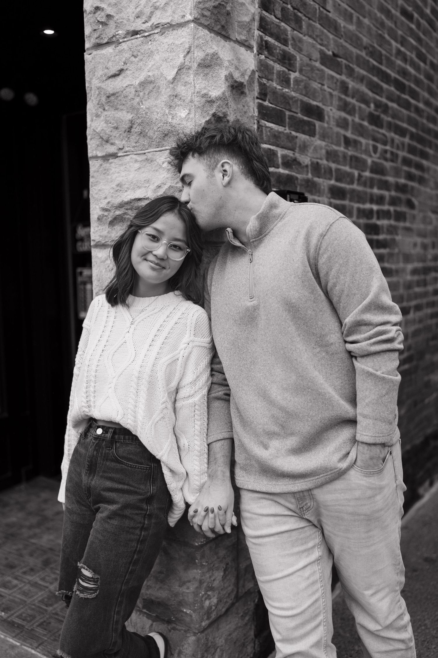 A romantic black and white portrait of a couple leaning against a brick wall. noblesville Indiana, indianapolis, cinematic, black and white