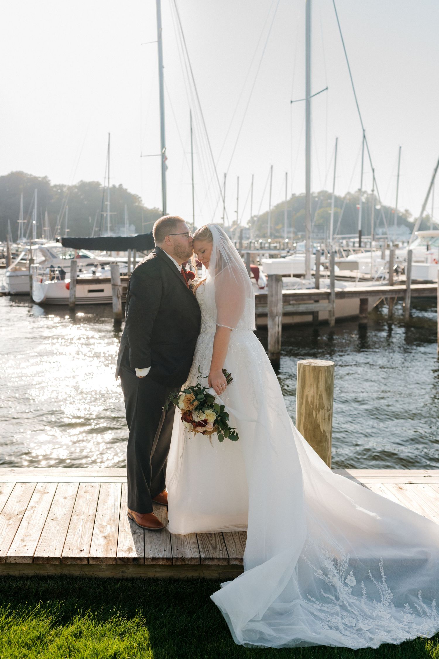 Romantic wedding photos on a wooden dock with boats and marina in the background.