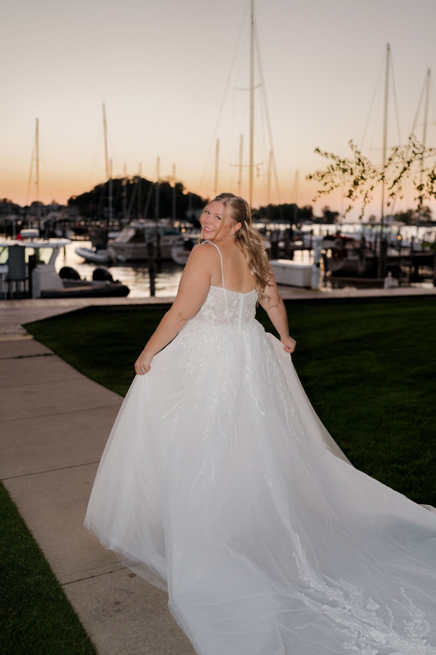 Wedding dress train flowing beautifully against marina backdrop at dusk.