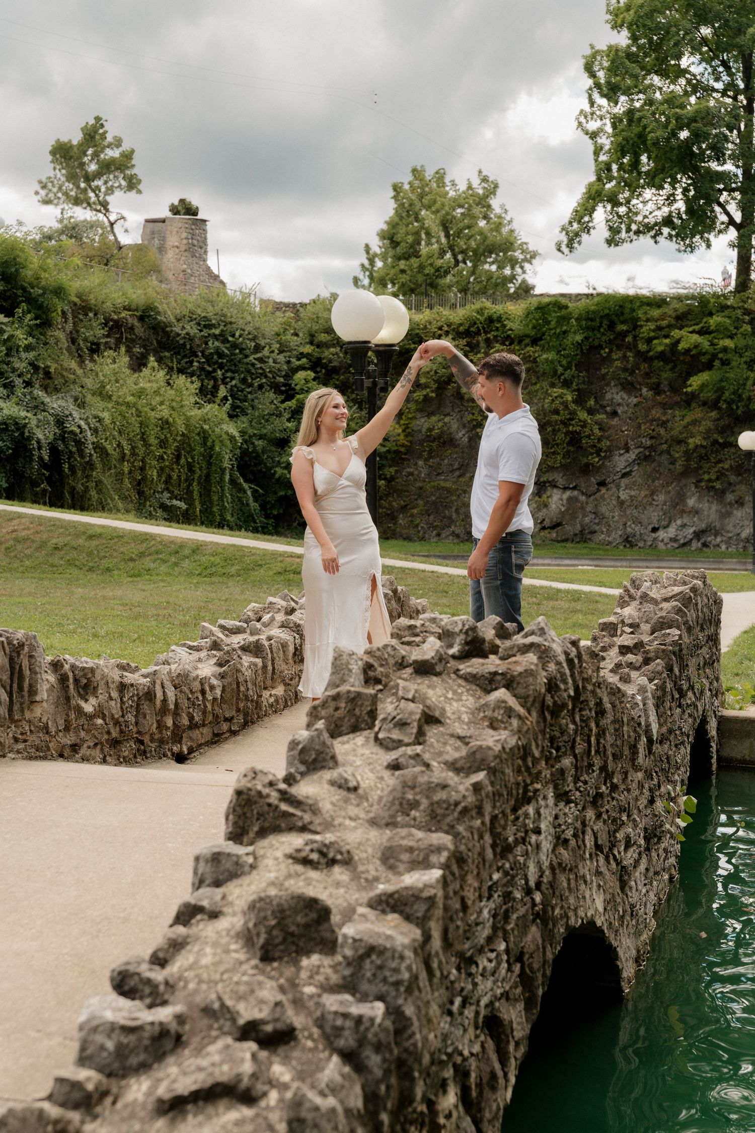 Couple playing with balloon on stone bridge near castle ruins.
