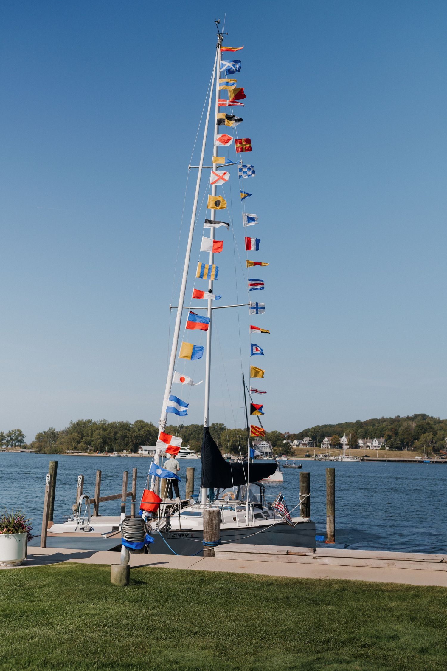 Colorful nautical flags flying on poles along a waterfront dock on a sunny day.