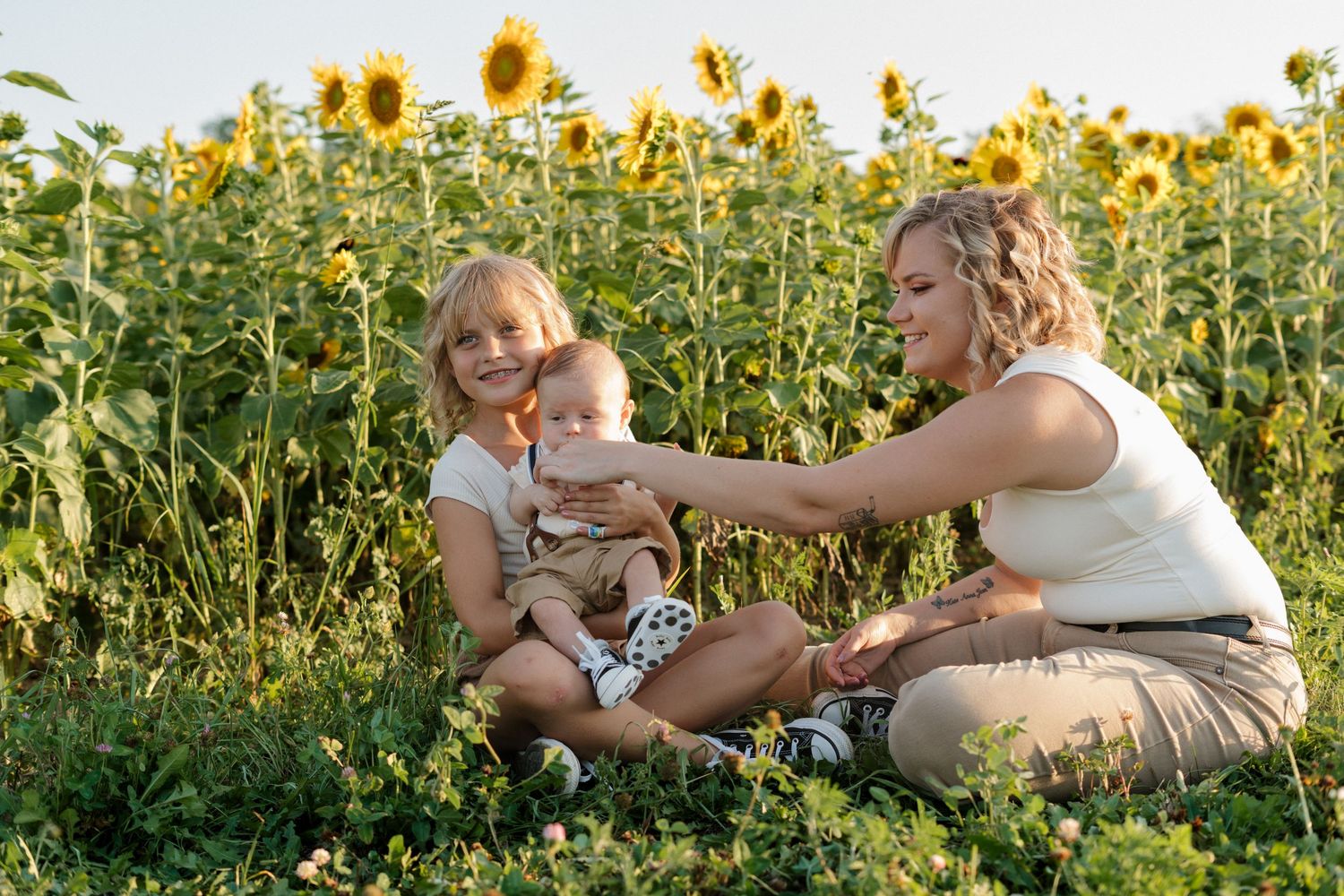 Family members laying together in a blooming sunflower field during a summer photo session.