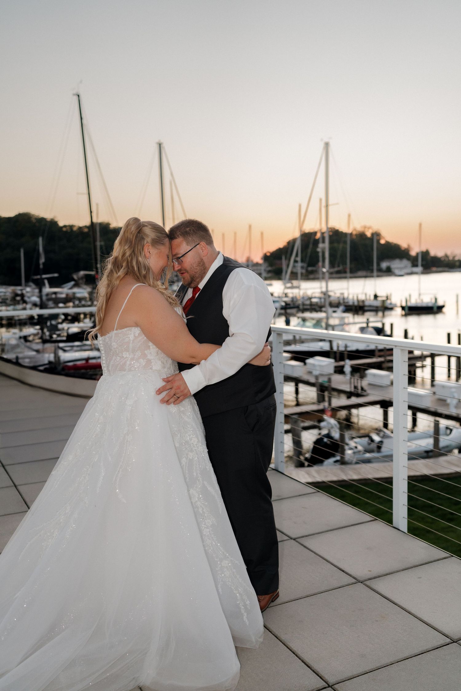 Romantic couple portraits at sunset with marina and sailboats in background.