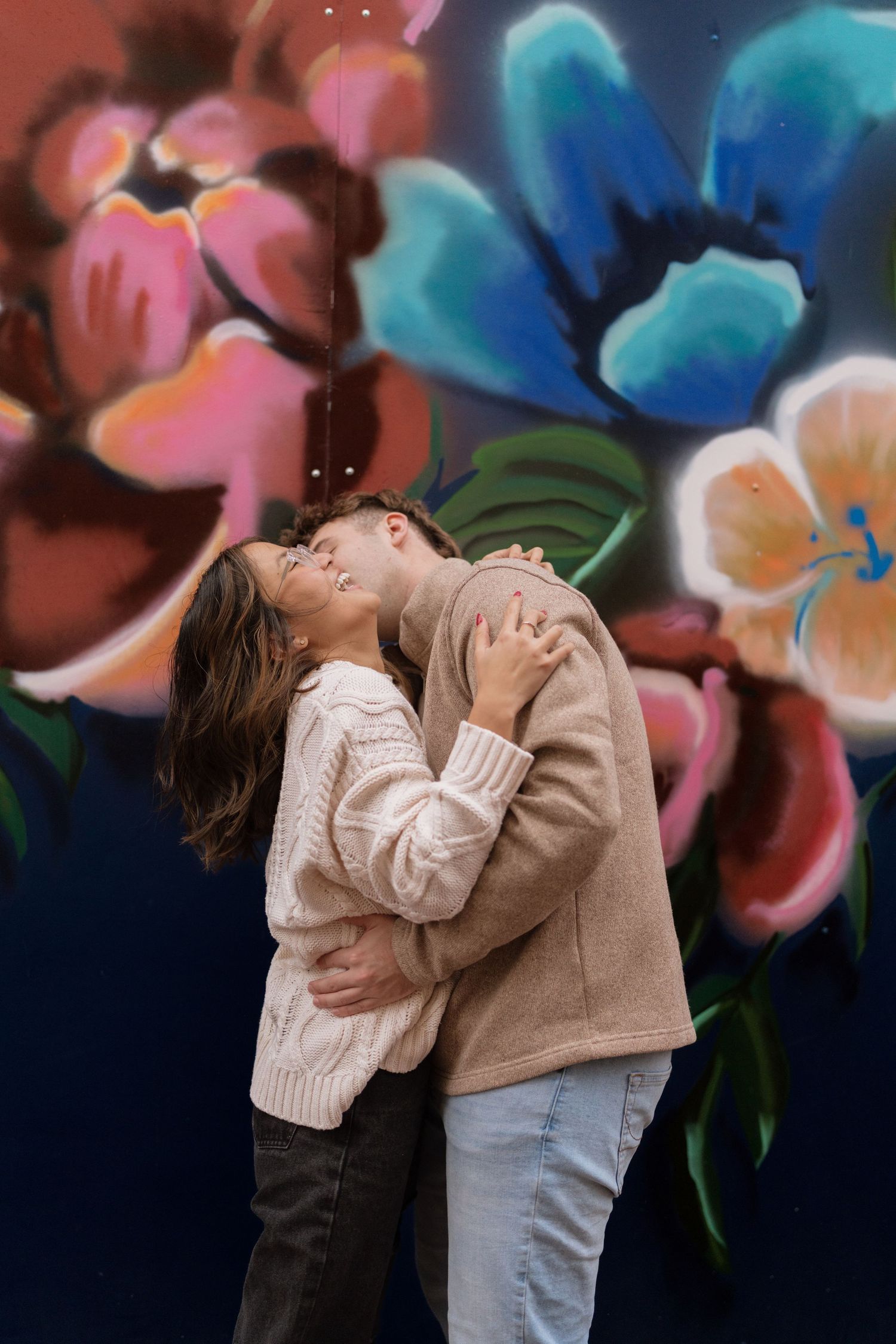 Romantic couple embracing against a colorful floral background with blue and pink tones.