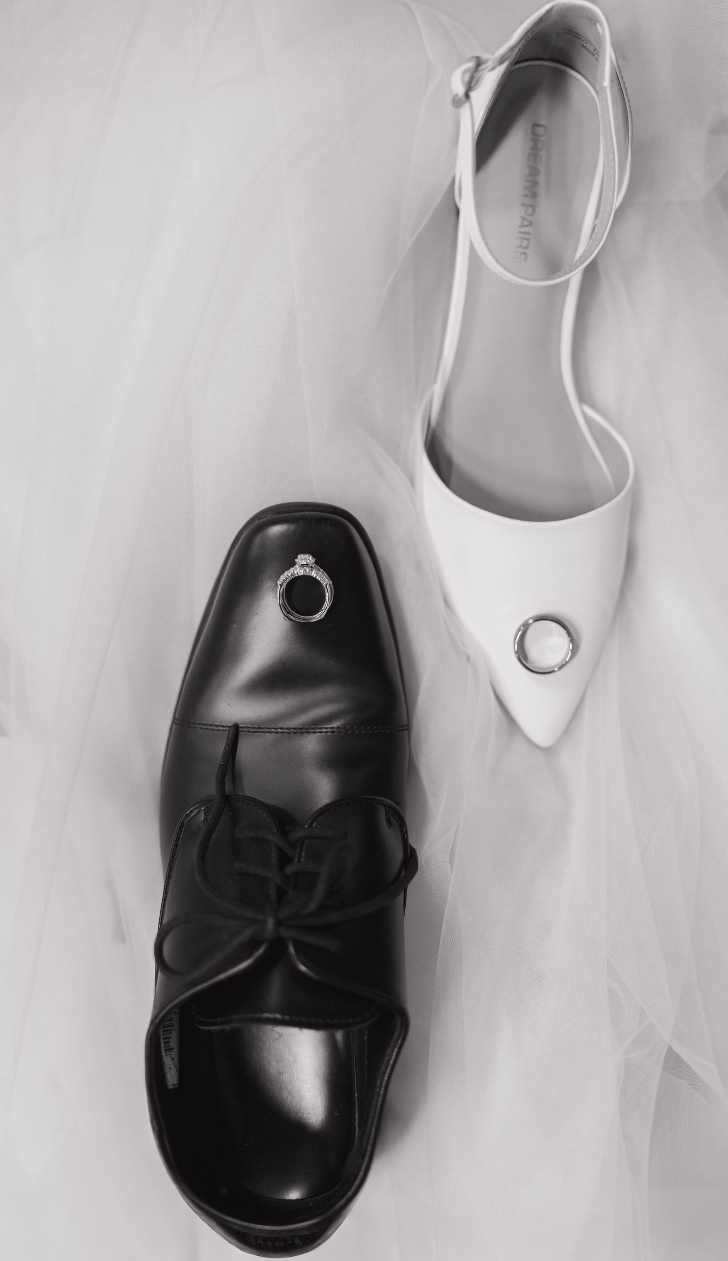Wedding shoes arranged artistically showing black dress shoes and white bridal heels.