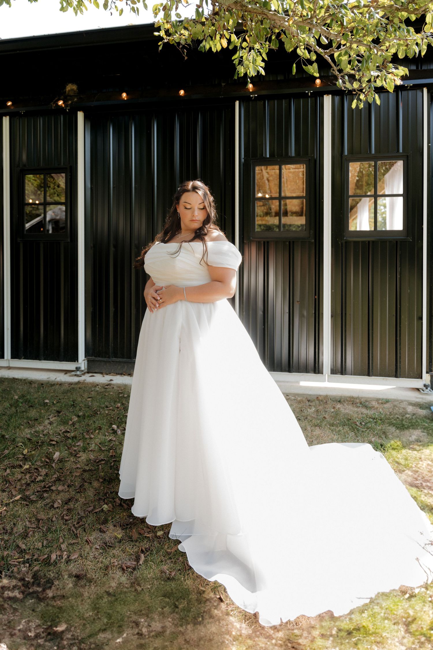 Flowing white wedding dress being showcased outdoors against natural scenery.