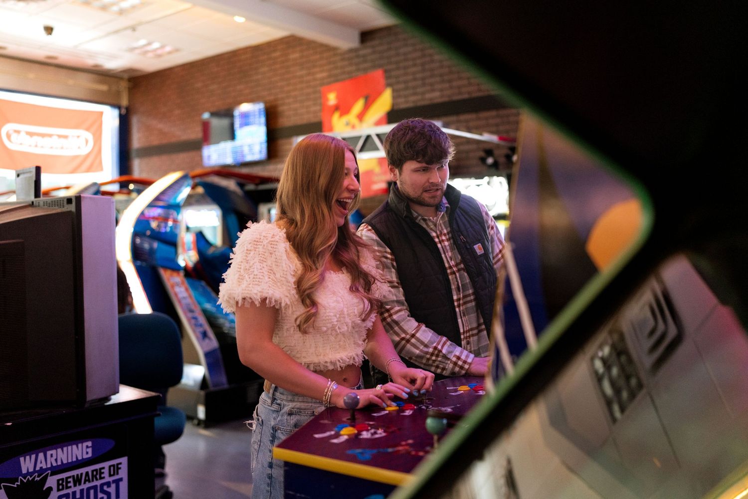 People playing arcade games at a retro gaming event with colorful lighting and vintage machines.