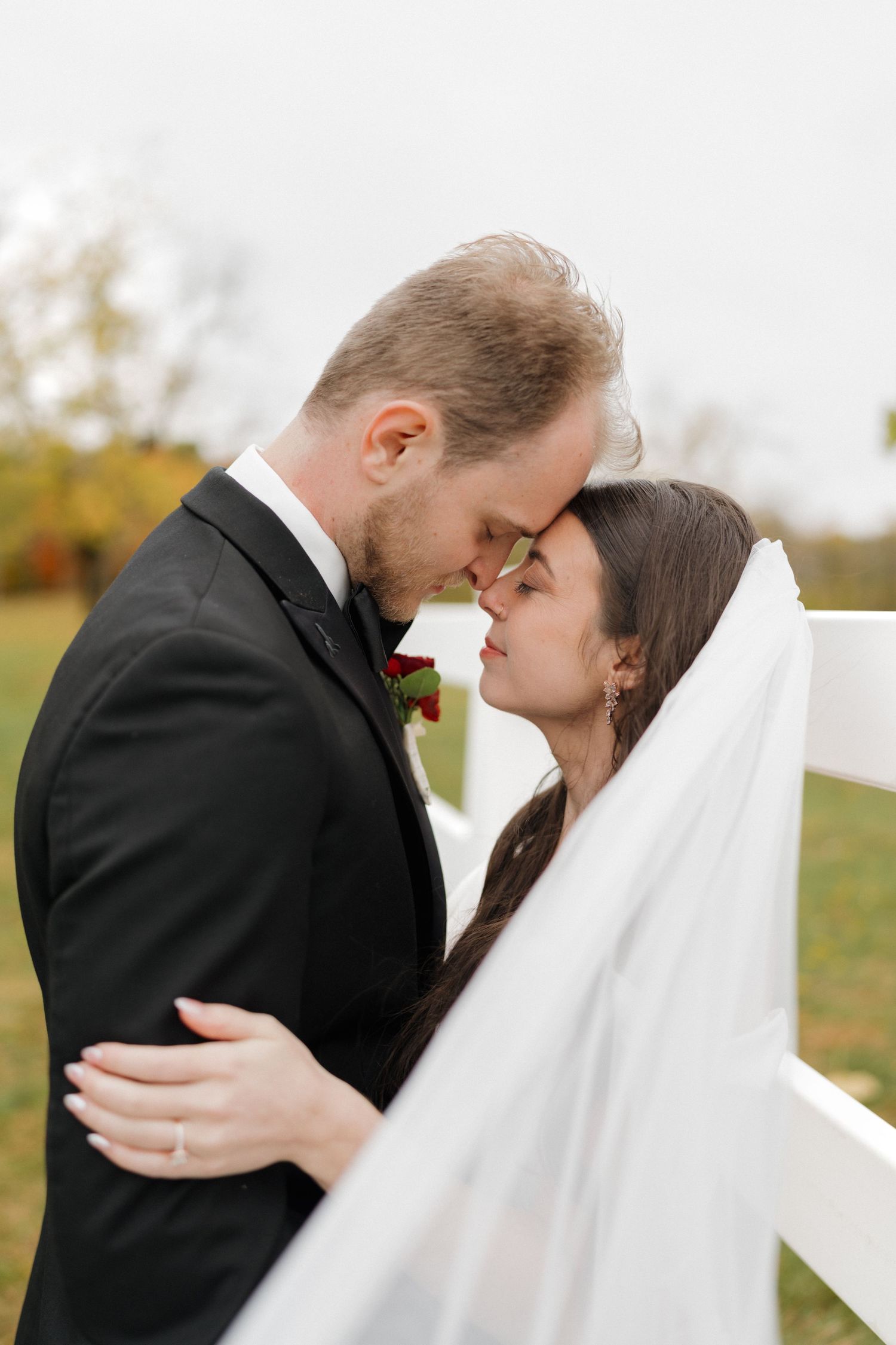 Intimate wedding portraits capture tender moments between newlyweds against white backdrop.