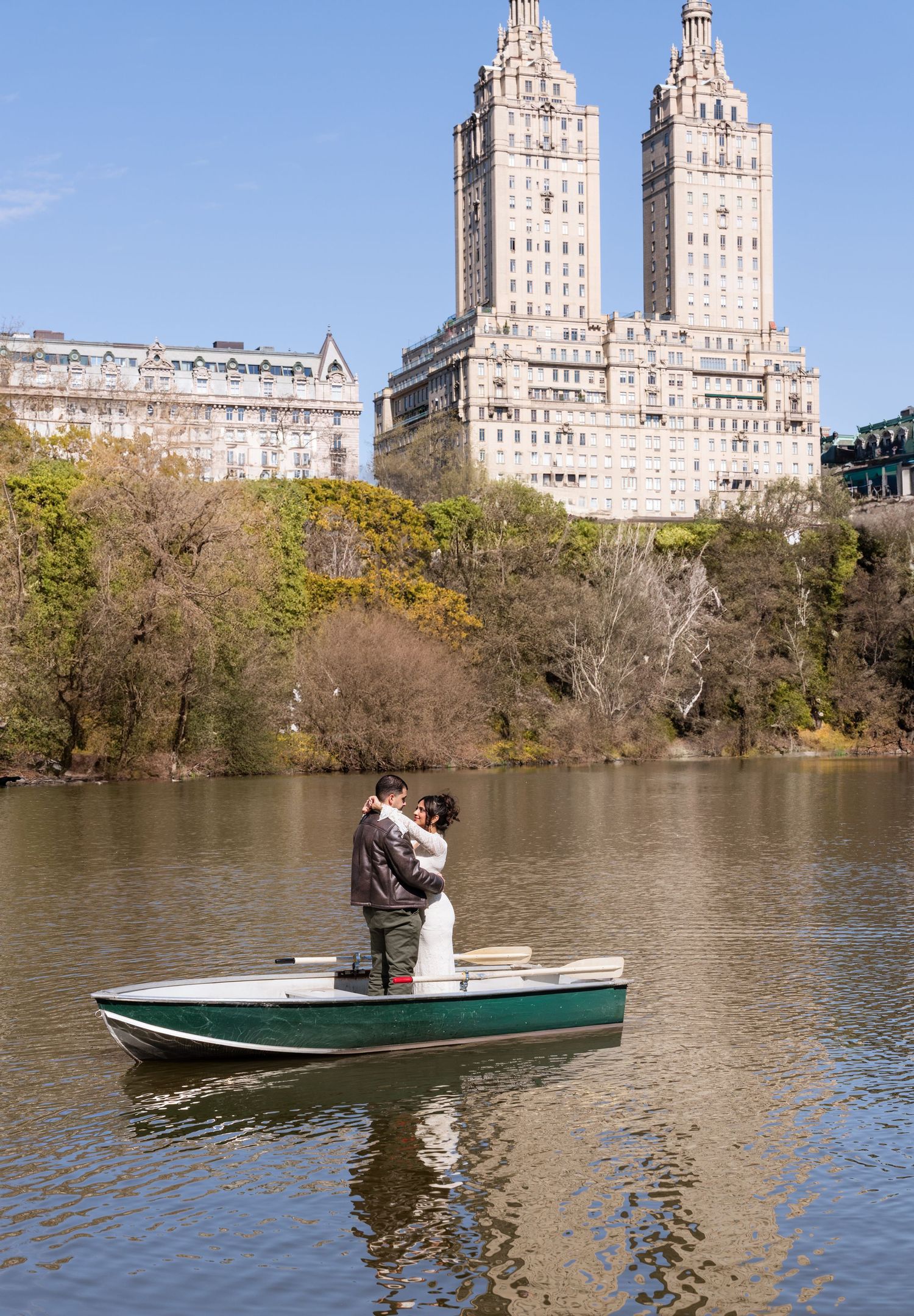 Couple sharing a romantic kiss on a rowboat on The Lake in Central Park with the San Remo building backdrop.