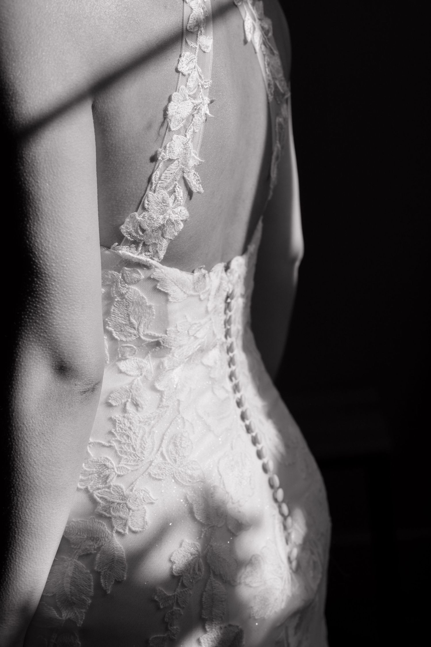 Close-up details of delicate lace appliques on the back of a white wedding dress.