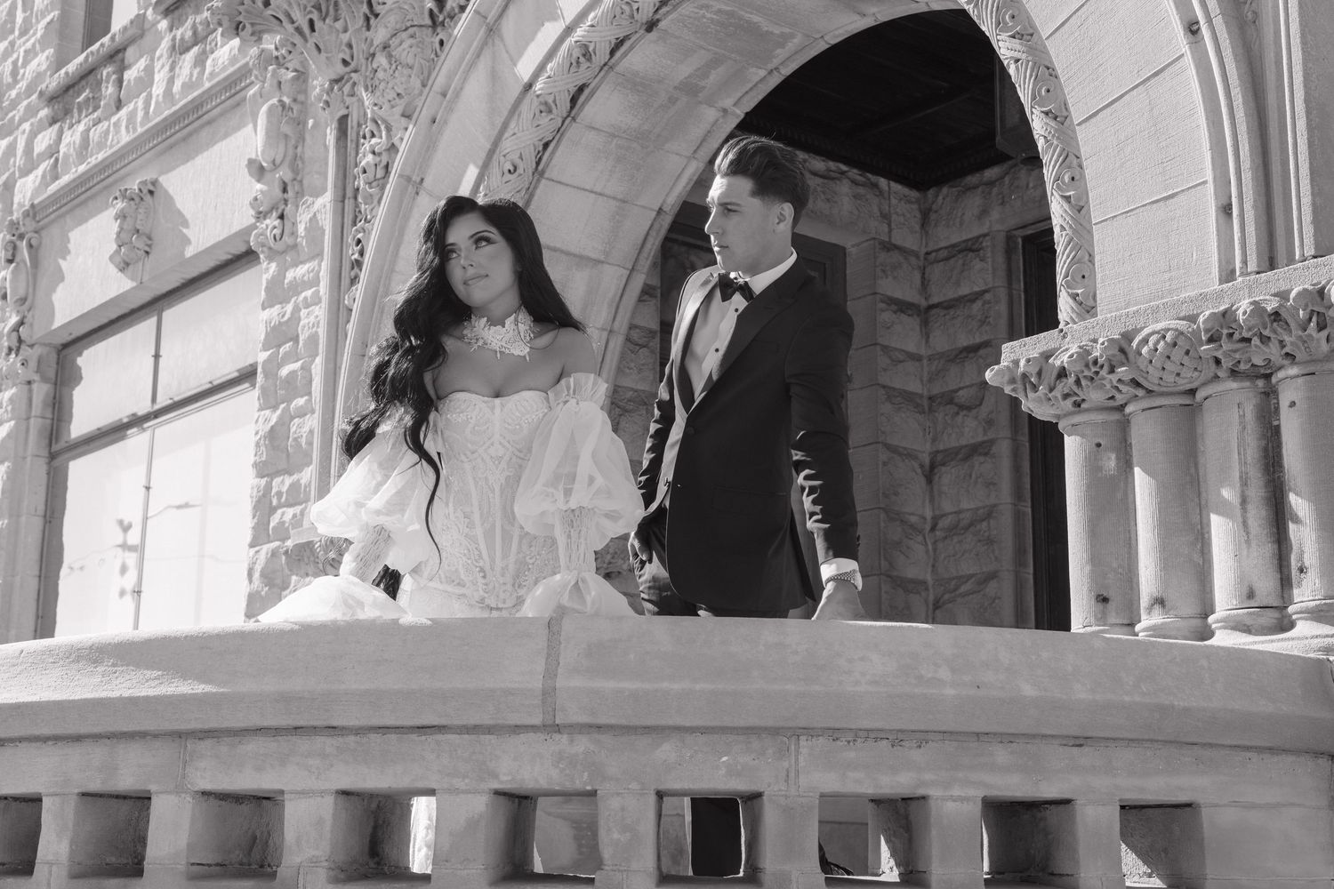 Elegant black and white wedding portraits captured in a grand architectural setting with ornate columns and arches.
