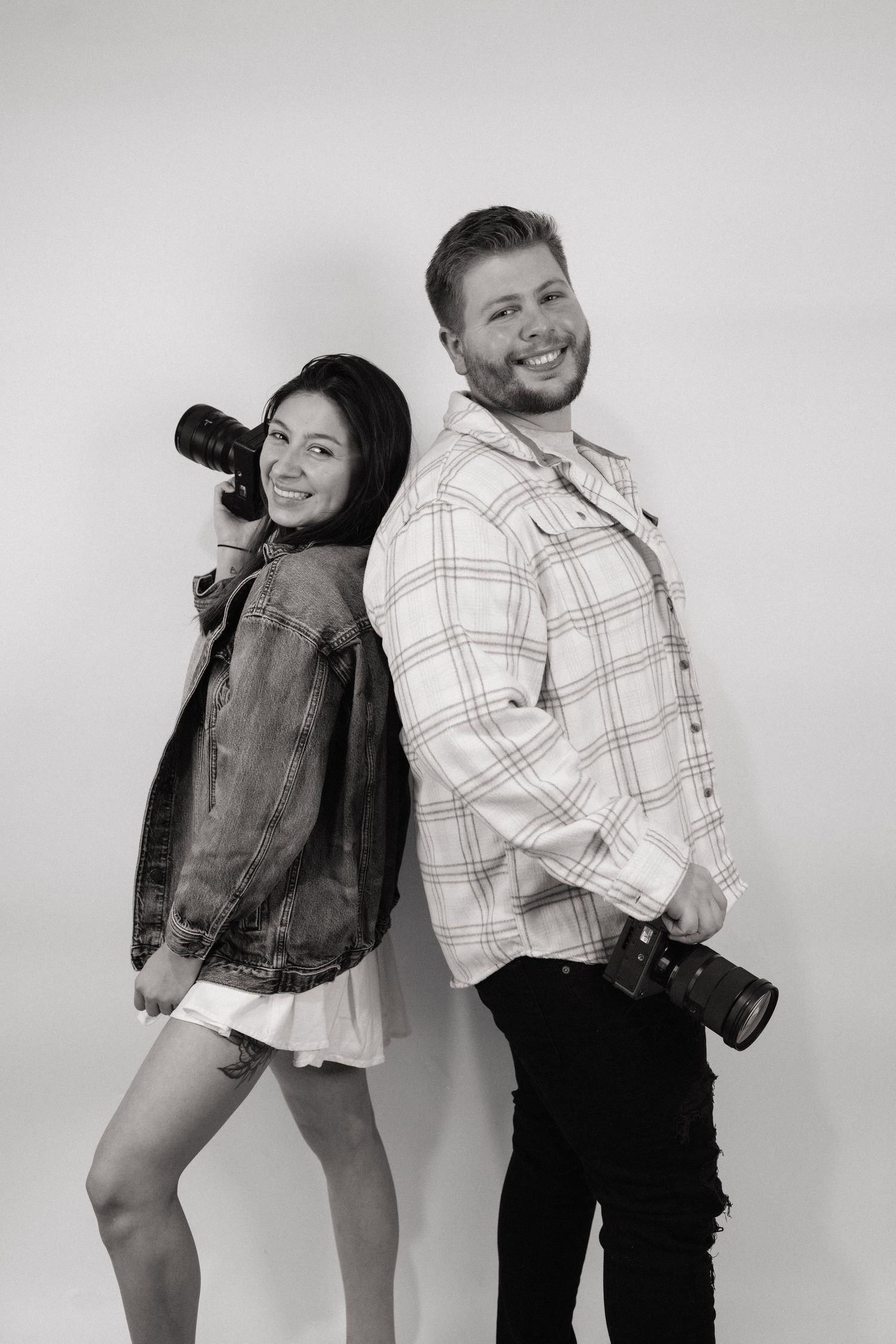 Fun and playful couple poses in casual outfits against a white studio backdrop.