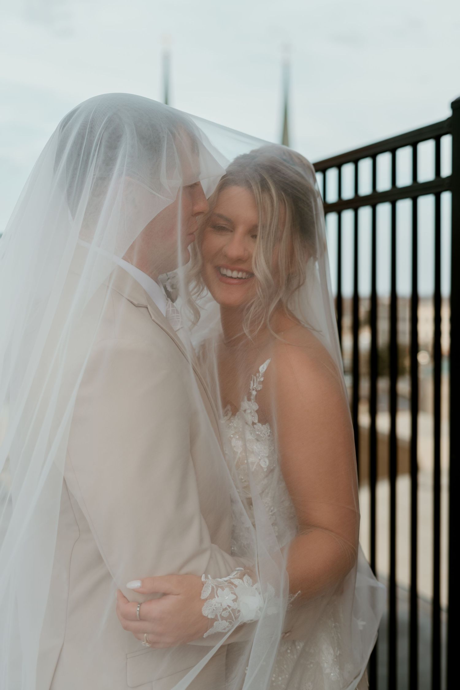 Romantic wedding portraits with flowing veil against metal fence backdrop. wedding, cinematic