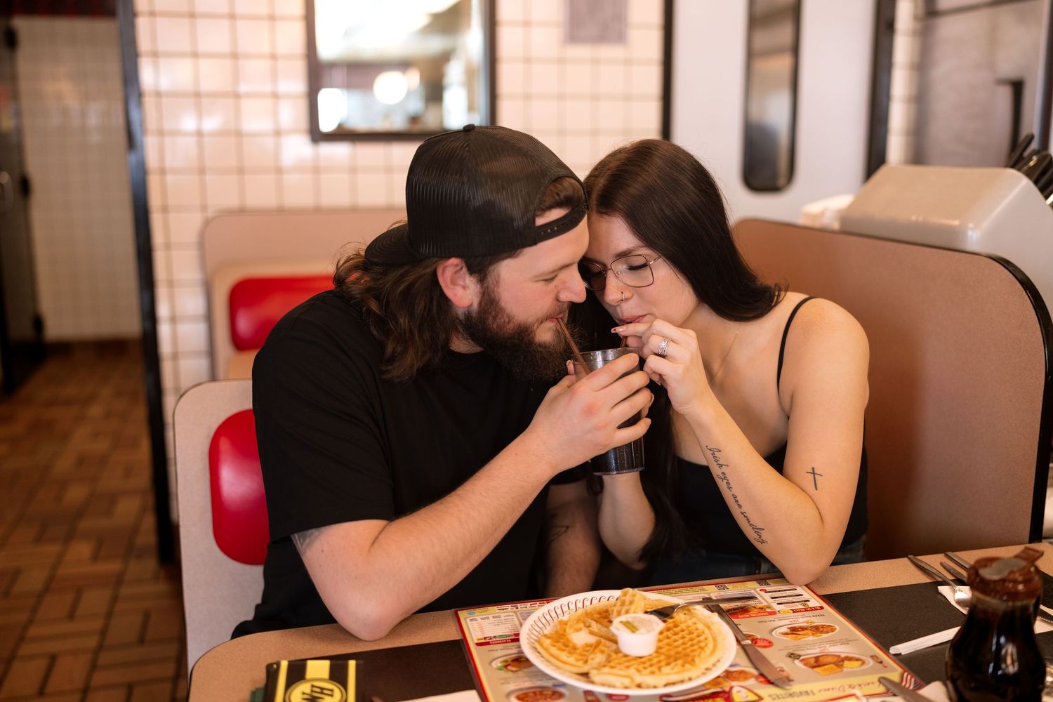 Couple sharing breakfast at a diner booth with pancakes on the table.