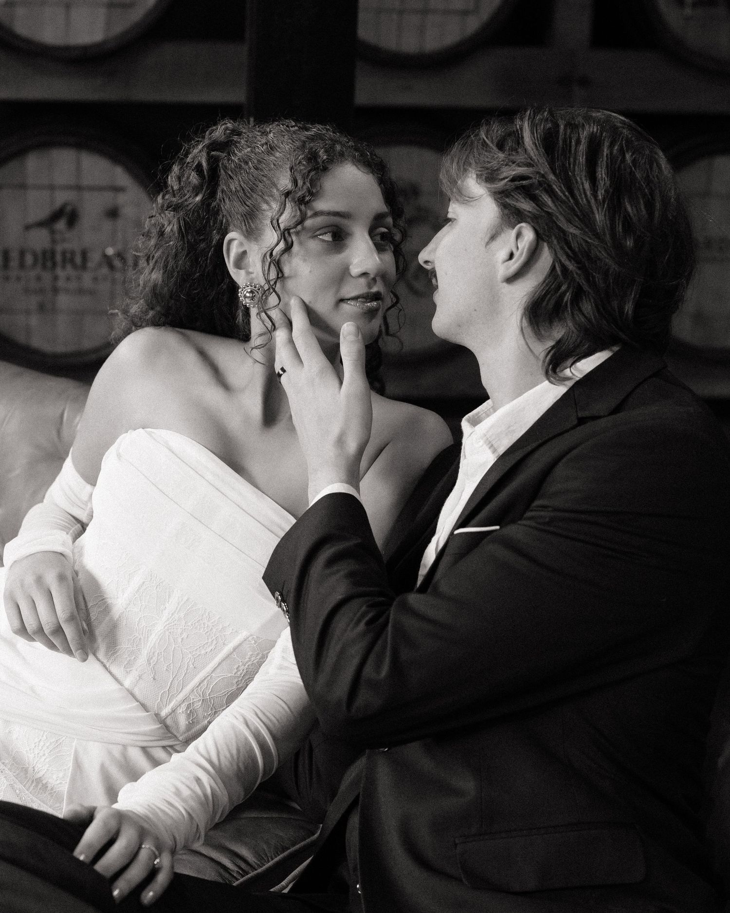 Black and white photo of a couple in formal wear sharing an intimate moment, man gently cupping woman's face.