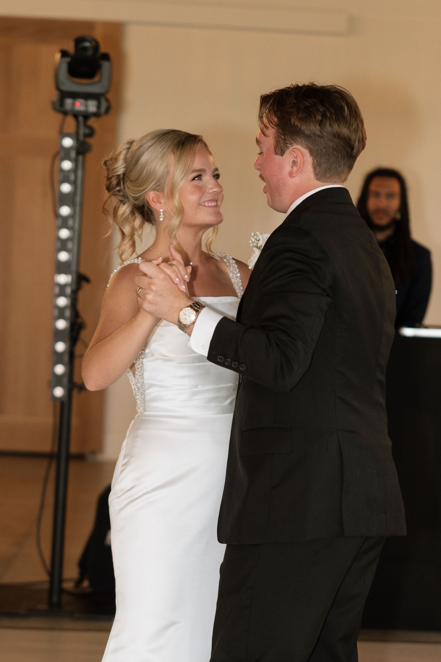 Bride and groom sharing their first dance, smiling lovingly at each other during wedding reception.