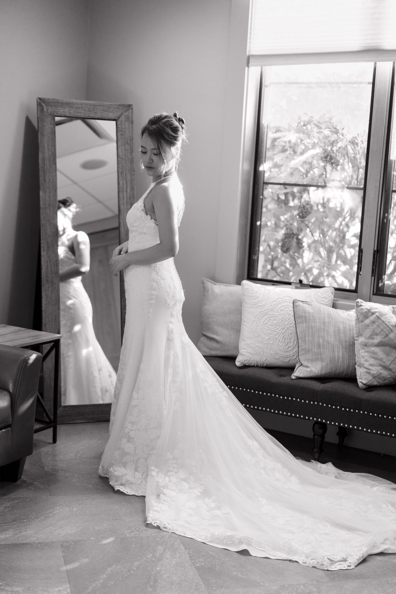 Bride's wedding dress train spreads elegantly across floor in bright room.