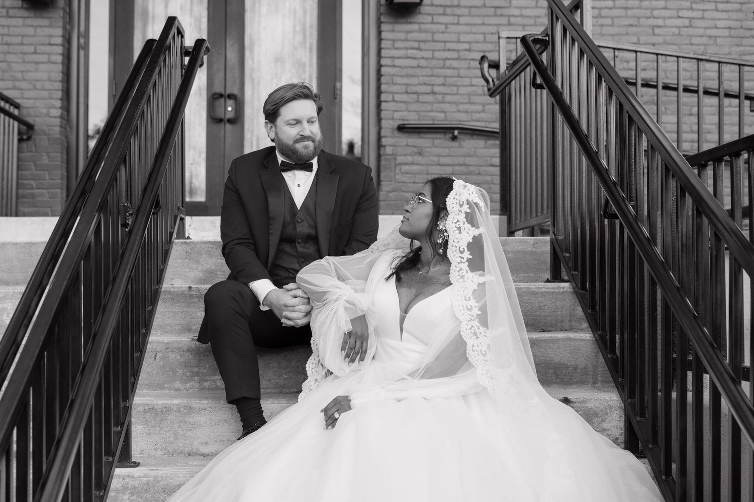 Wedding party members walking down brick steps with iron railings.