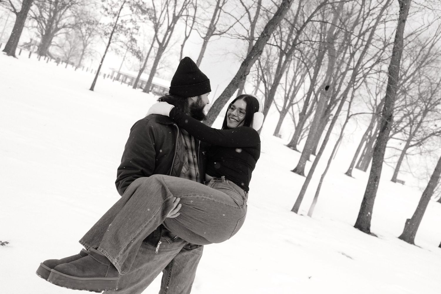 A couple walking through a snowy winter forest landscape.