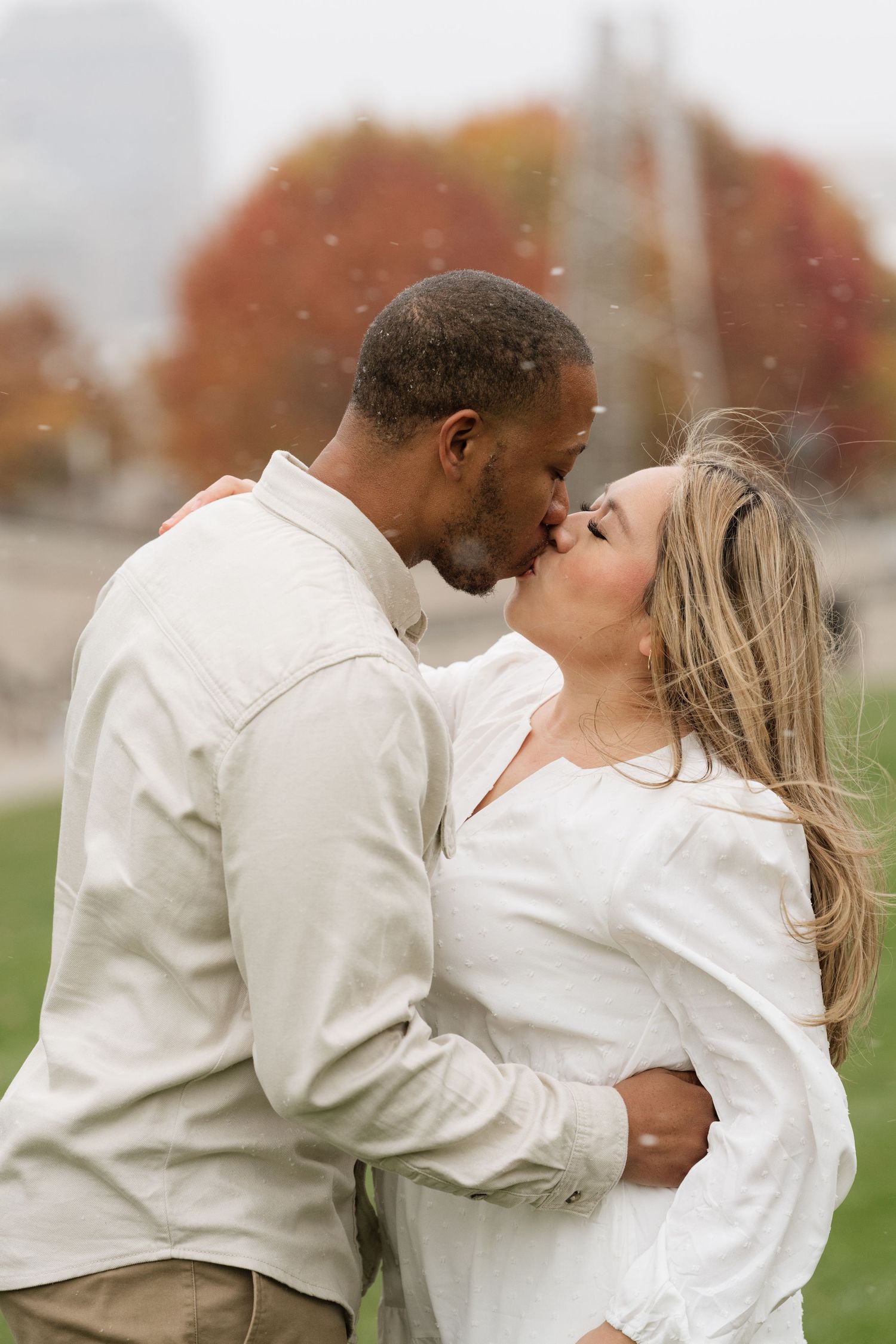 A romantic autumn photoshoot of a couple in white outfits embracing on a grassy field. maternity, fall session, Indianapolis Indiana