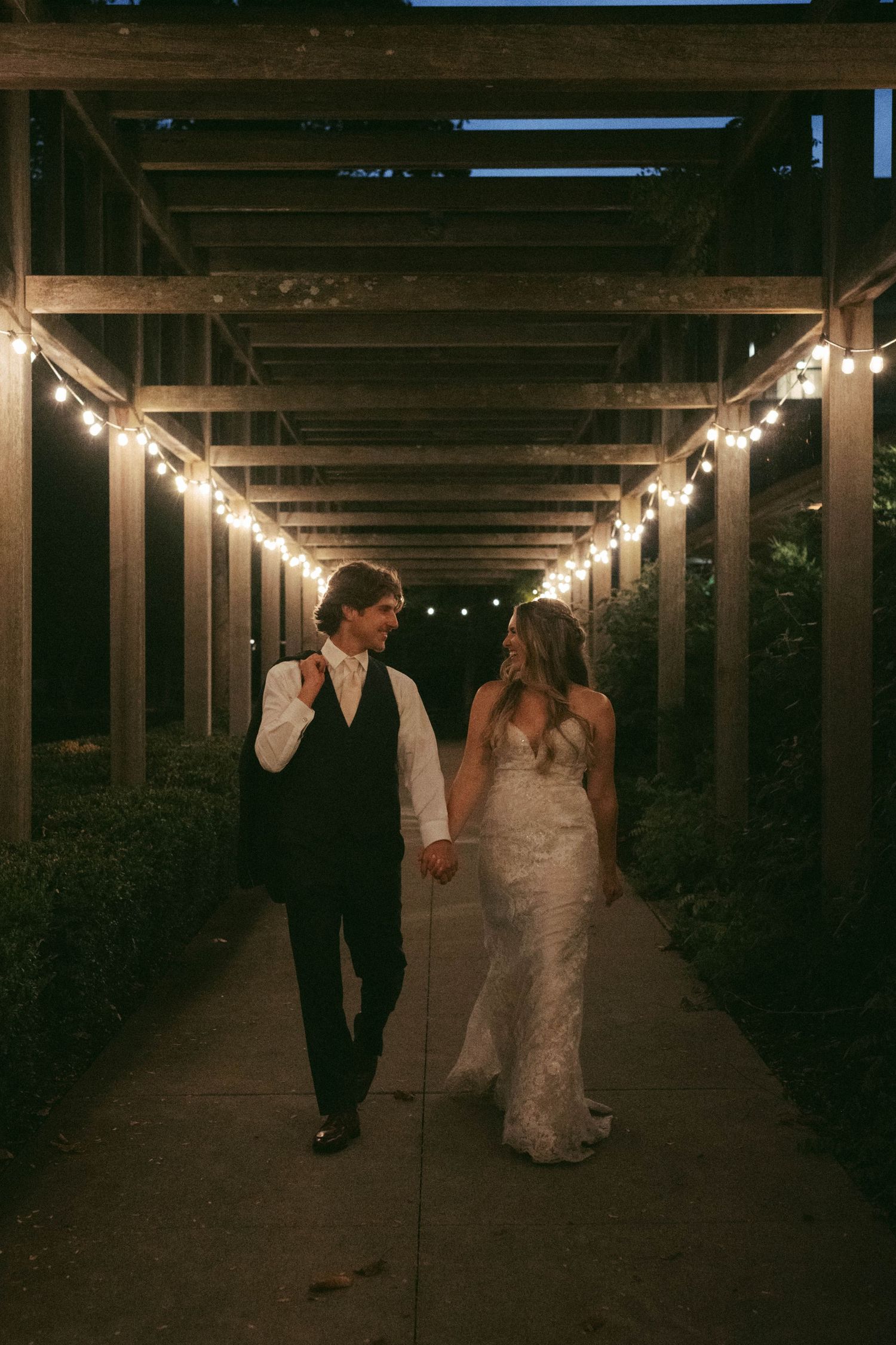 Couple walking through a dimly lit corridor with string lights overhead.