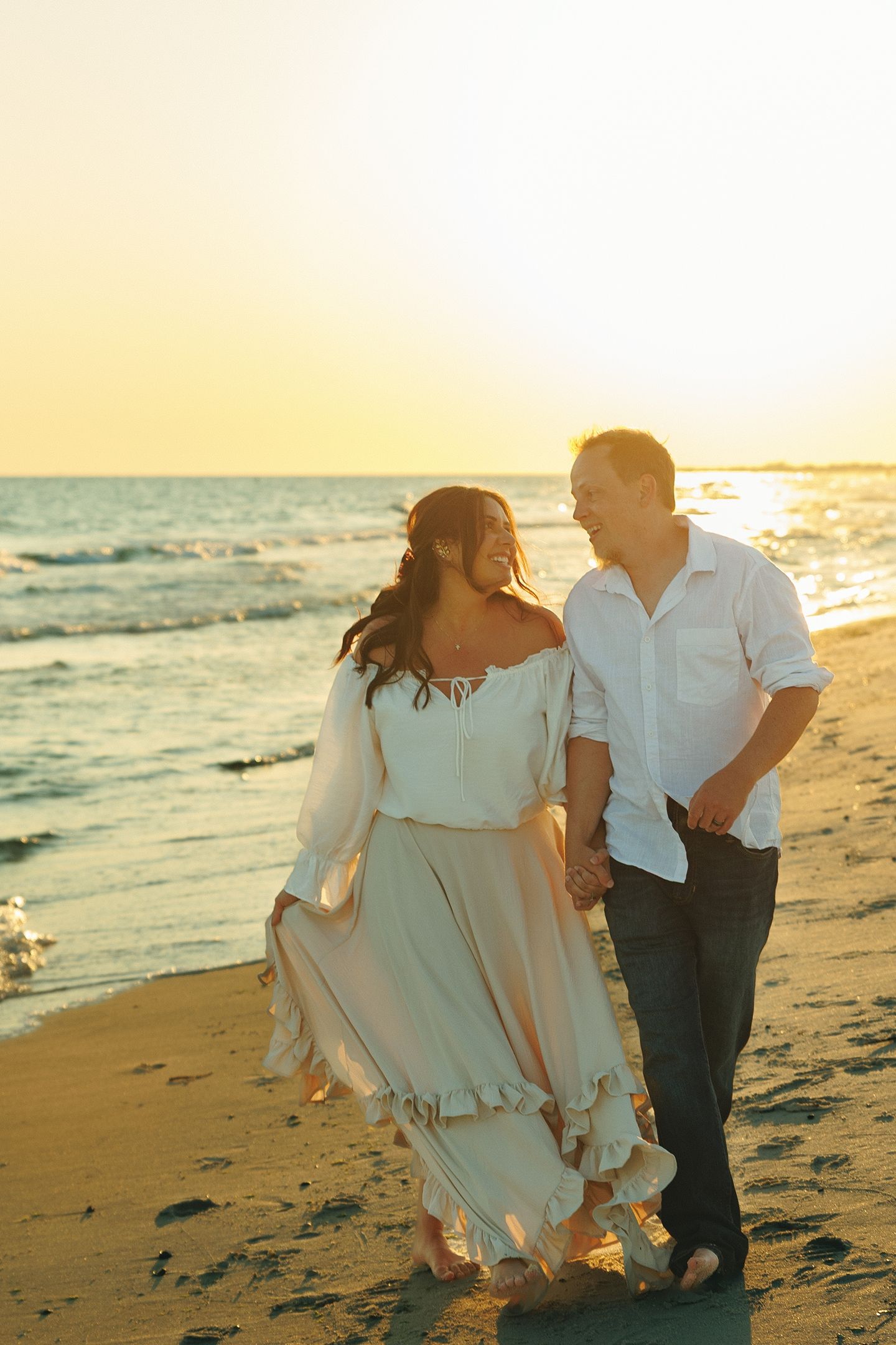 Romantic beach photoshoot at golden hour with flowing white dress.