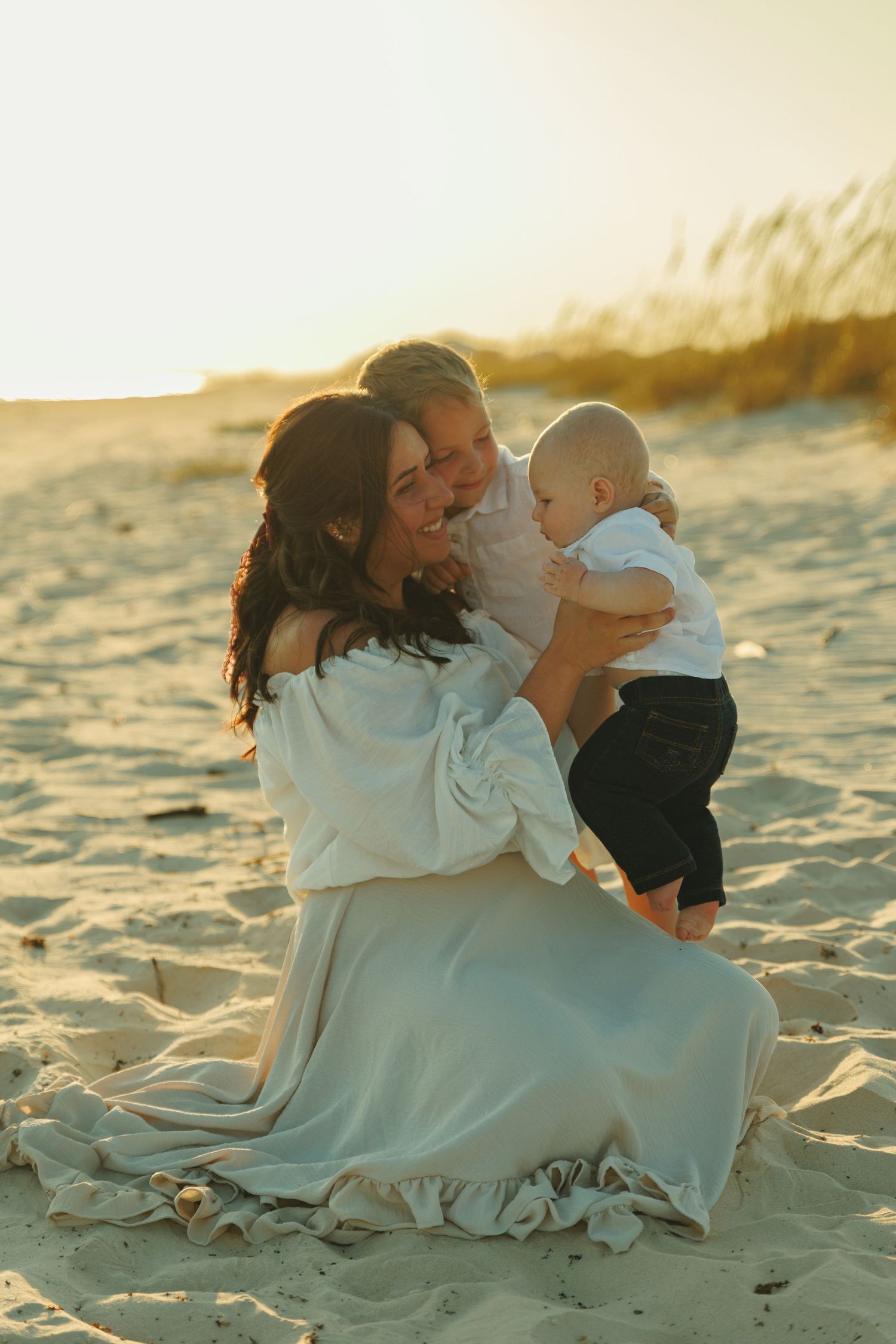 Family sharing tender moments together on a beach at sunset.
