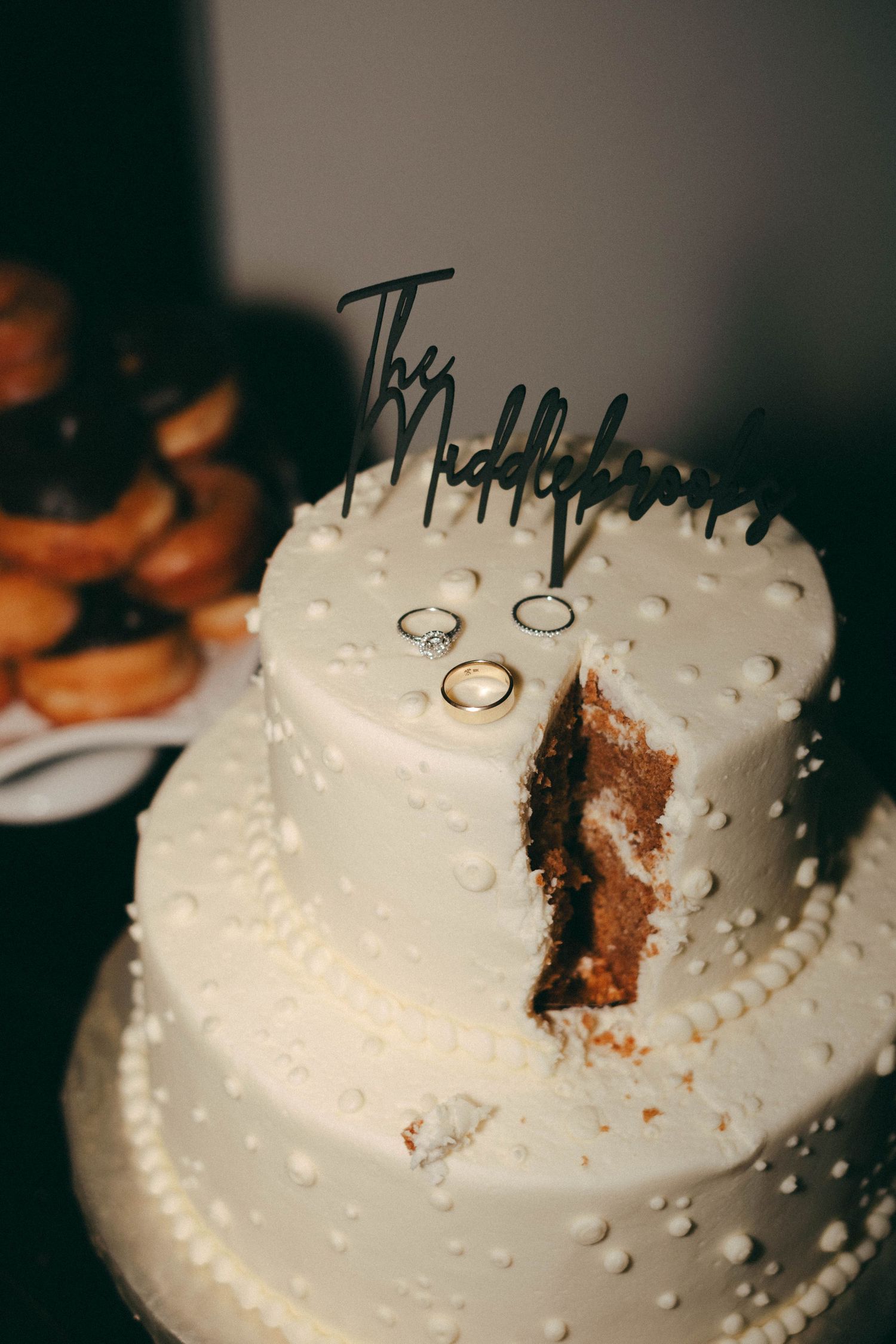 A white wedding cake with pearled decorations shows signs of being cut and served.