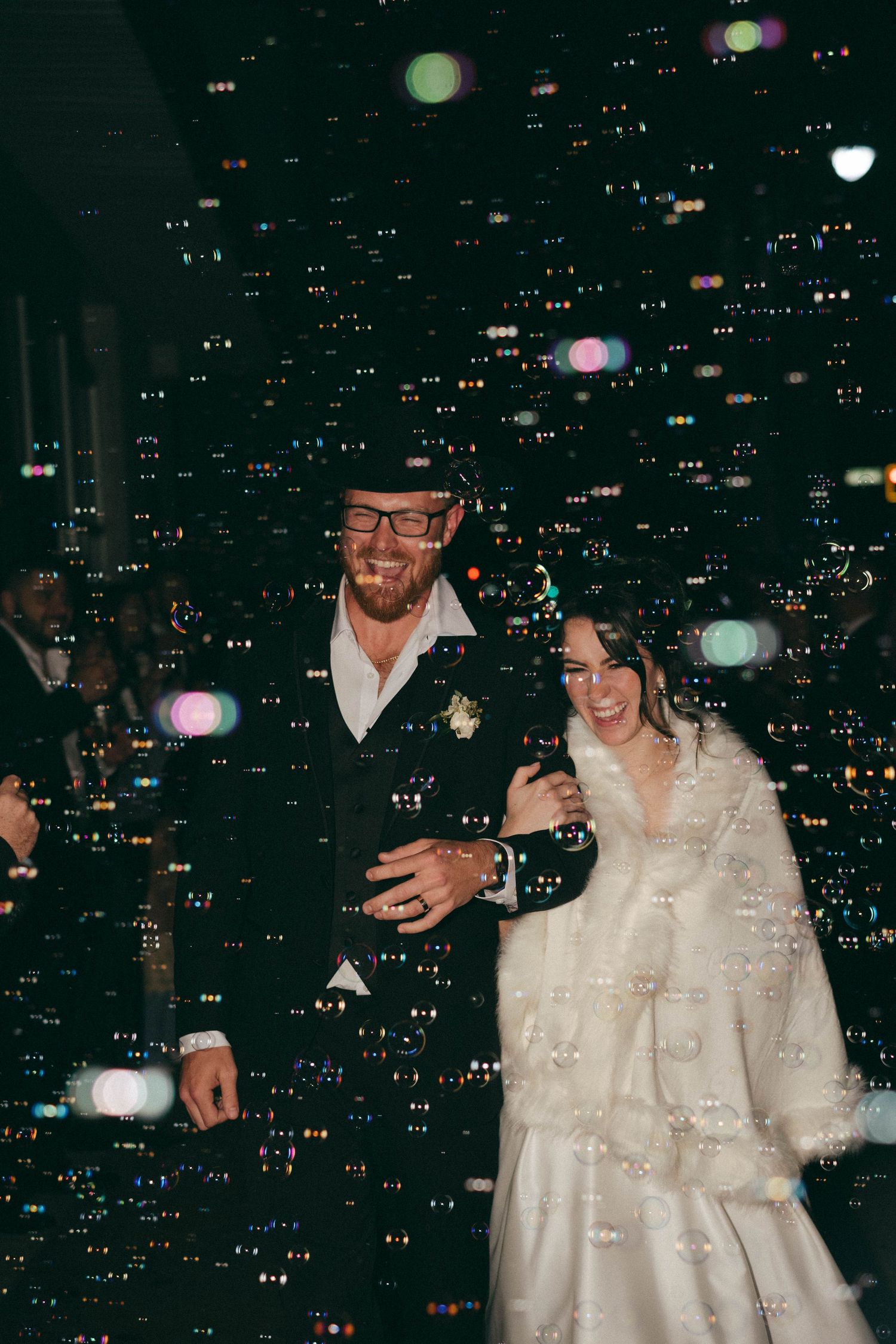 A couple celebrates their wedding night against a backdrop of glowing city lights and bokeh effects.