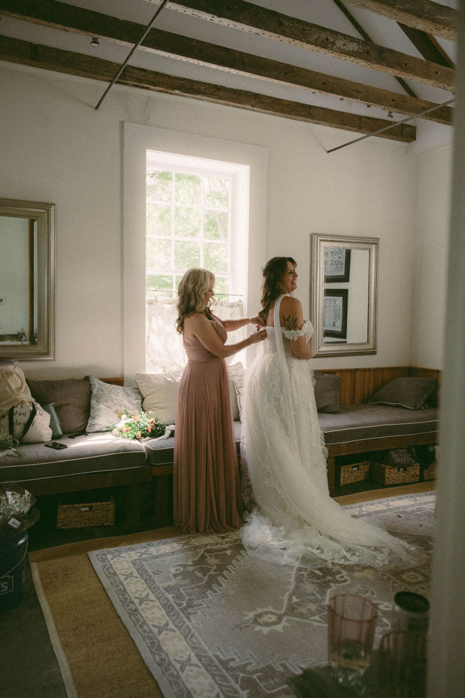 Wedding preparation scene in a bright white room with exposed wooden beams.
