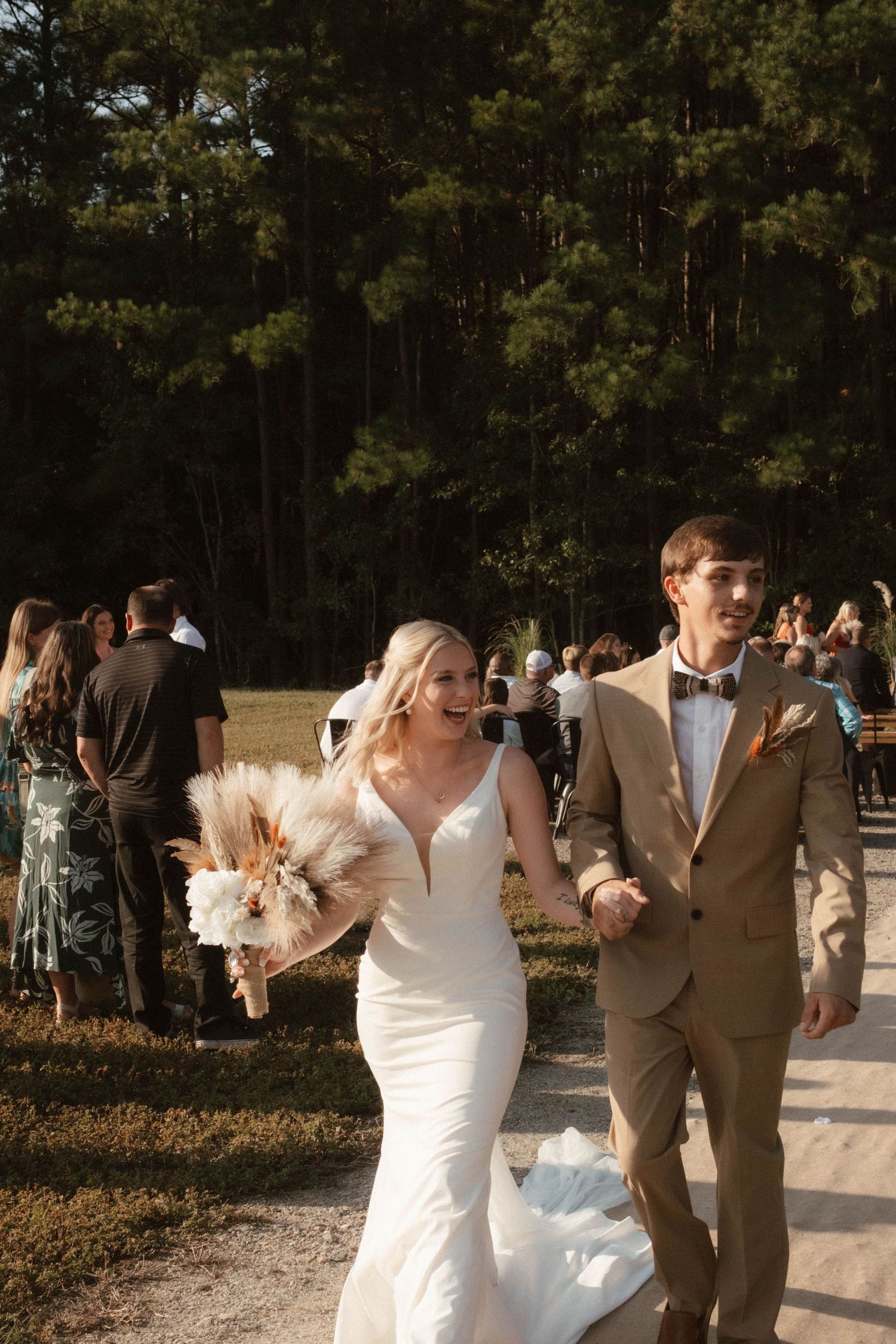 Wedding party members dance and celebrate outdoors during a sunny afternoon celebration.