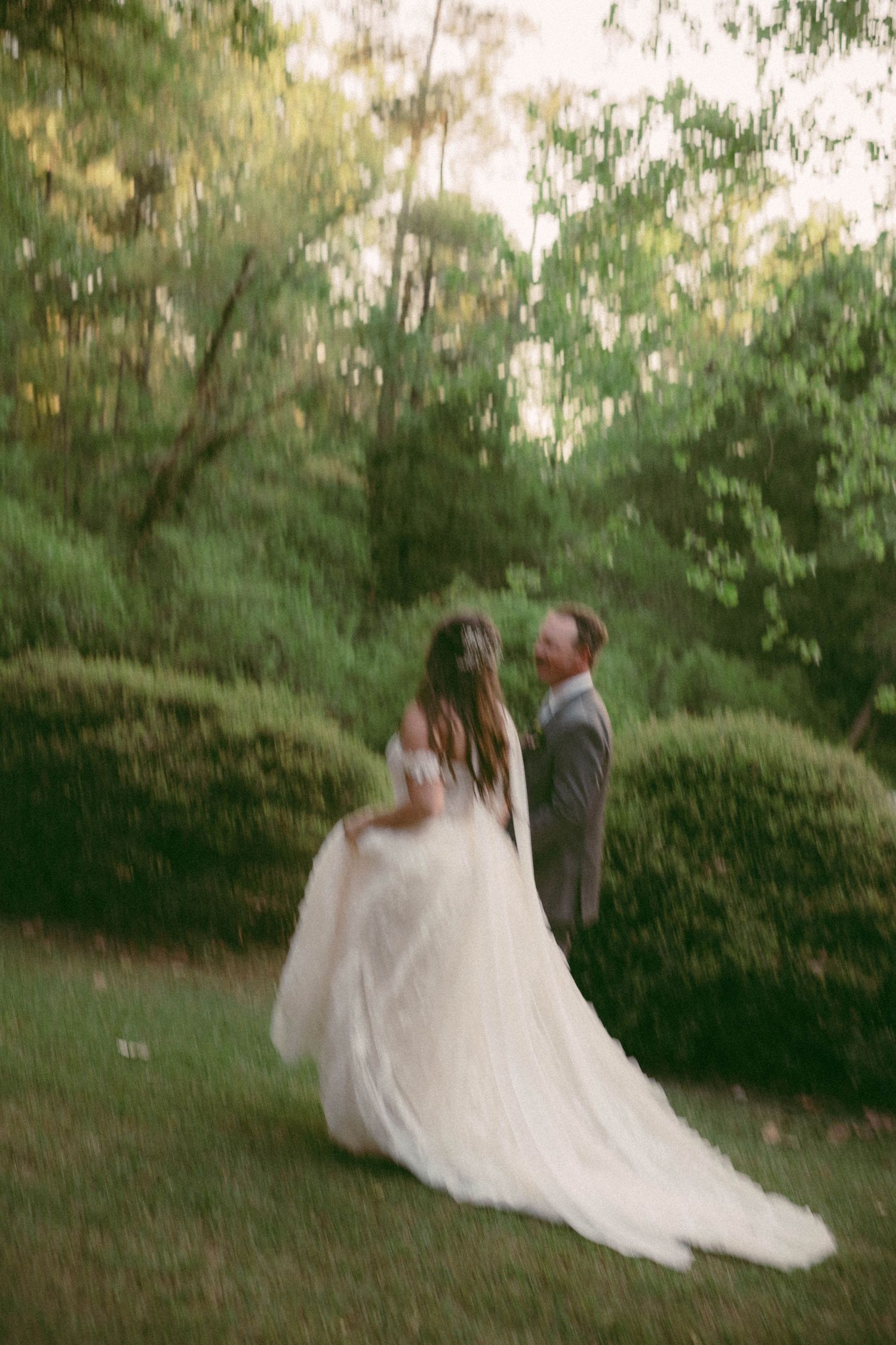 Couple dancing in a garden setting with flowing white wedding dress.
