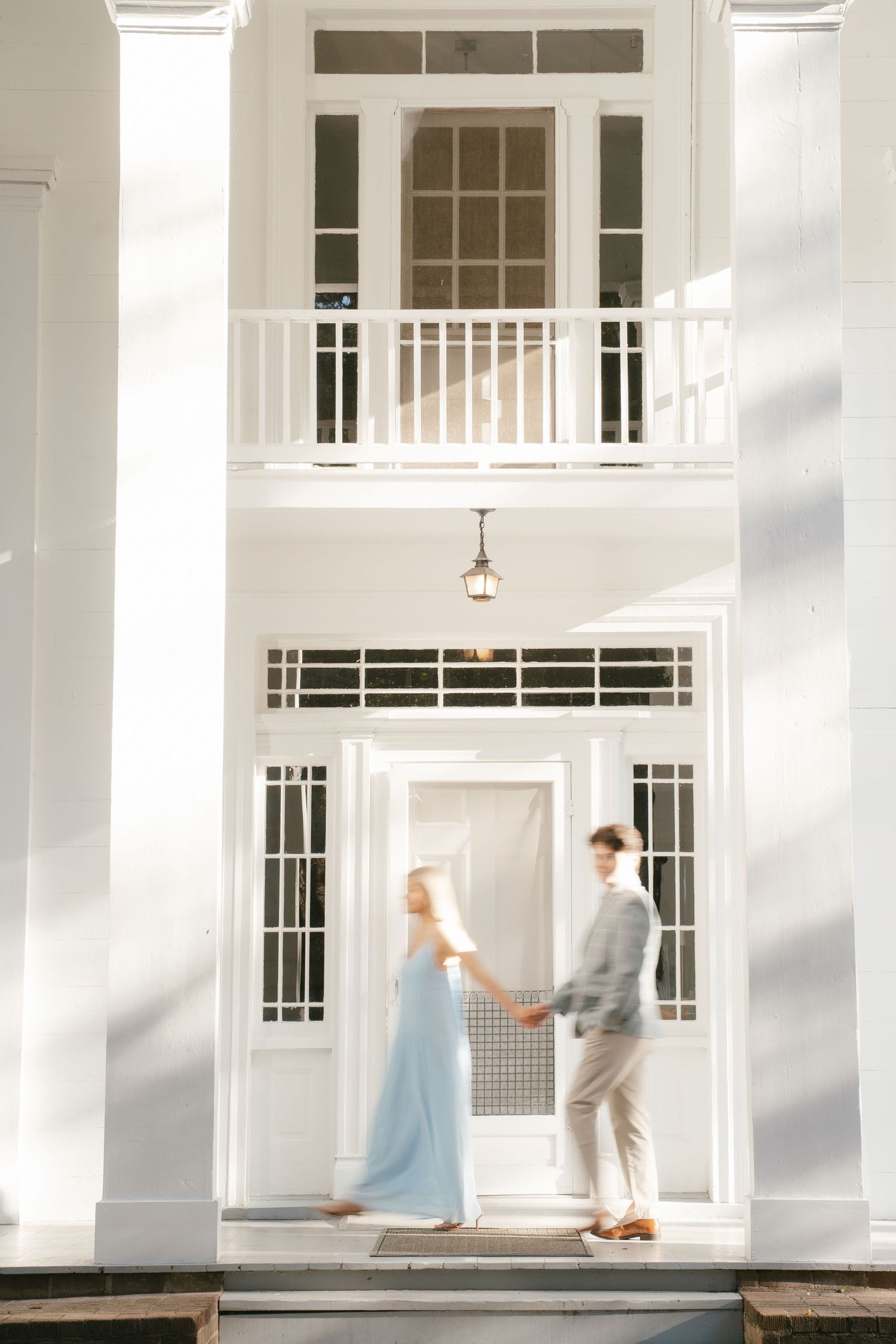 Artistic motion blur photo of a couple dancing in a white columned building interior.
