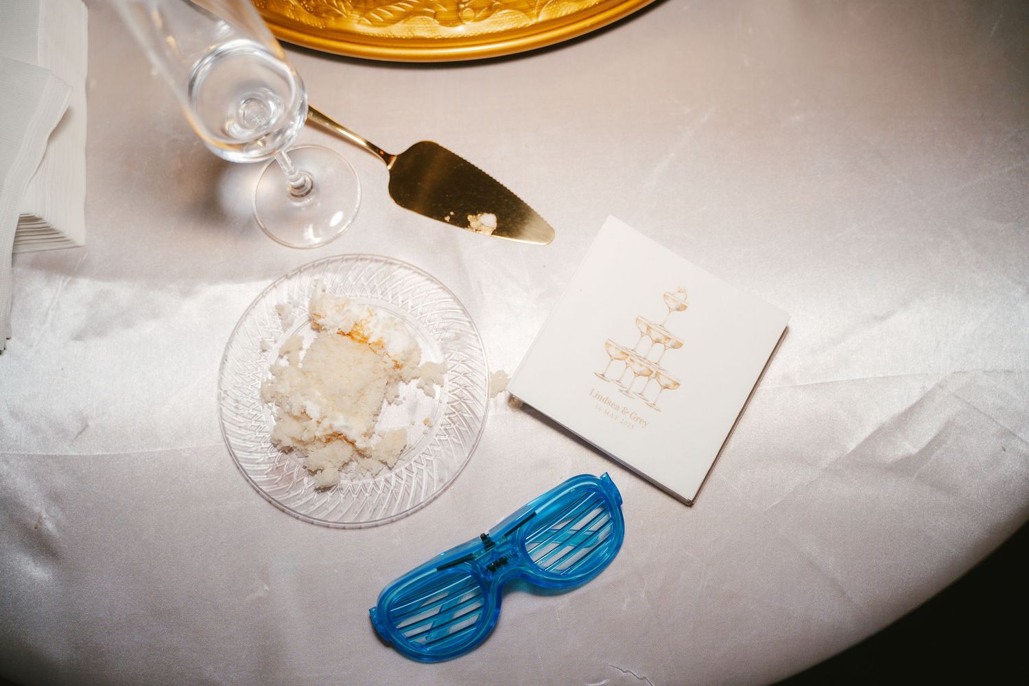 Wedding reception details with elegant glassware and place settings on a white tablecloth.