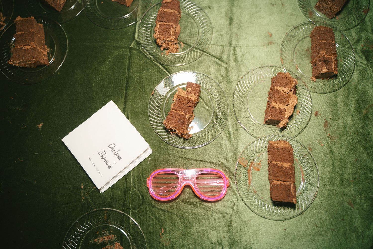 Table settings with chocolate desserts and pink sunglasses at a wedding reception.
