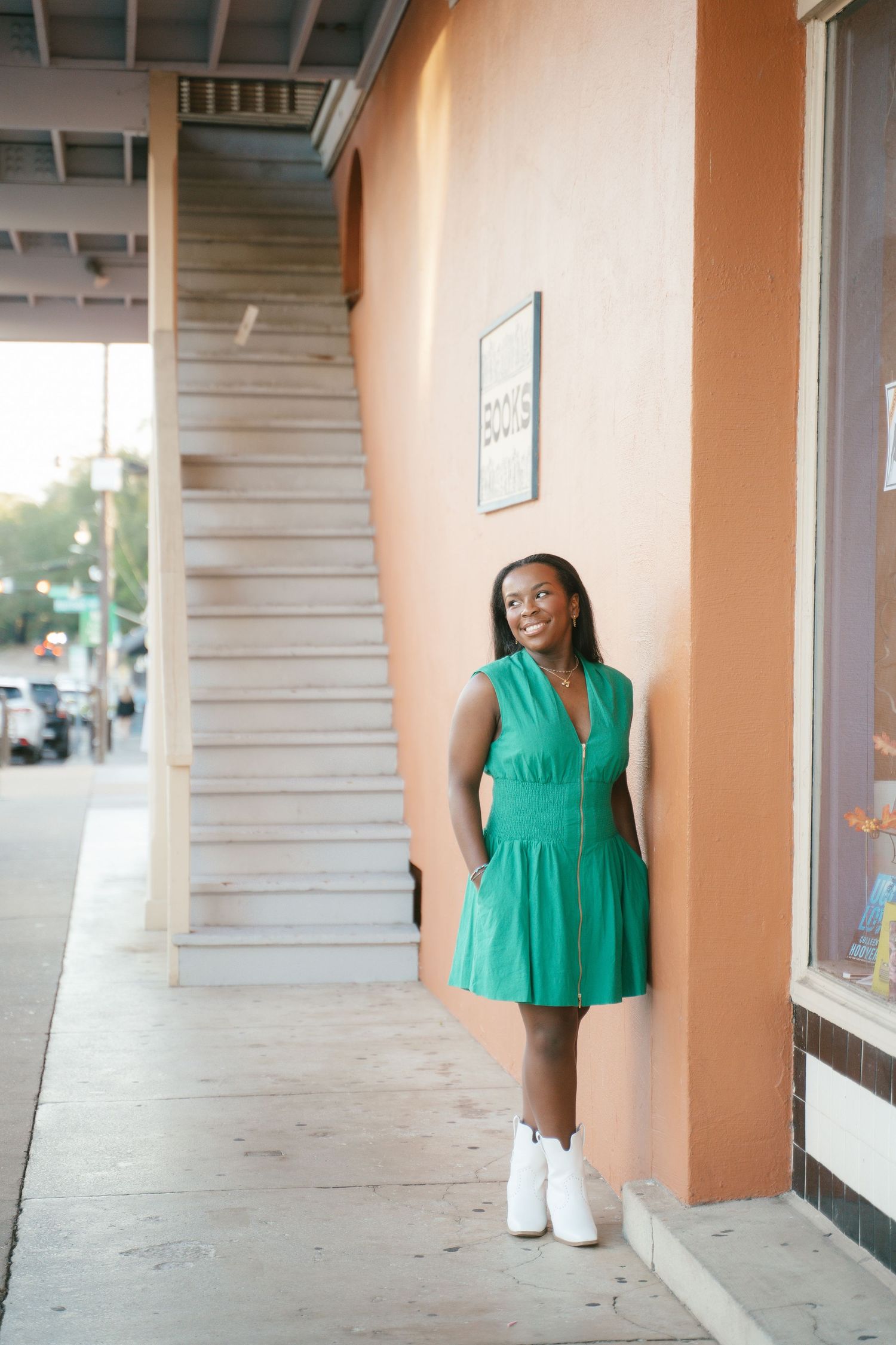 Casual summer fashion look with a bright green dress and white boots in an urban setting.