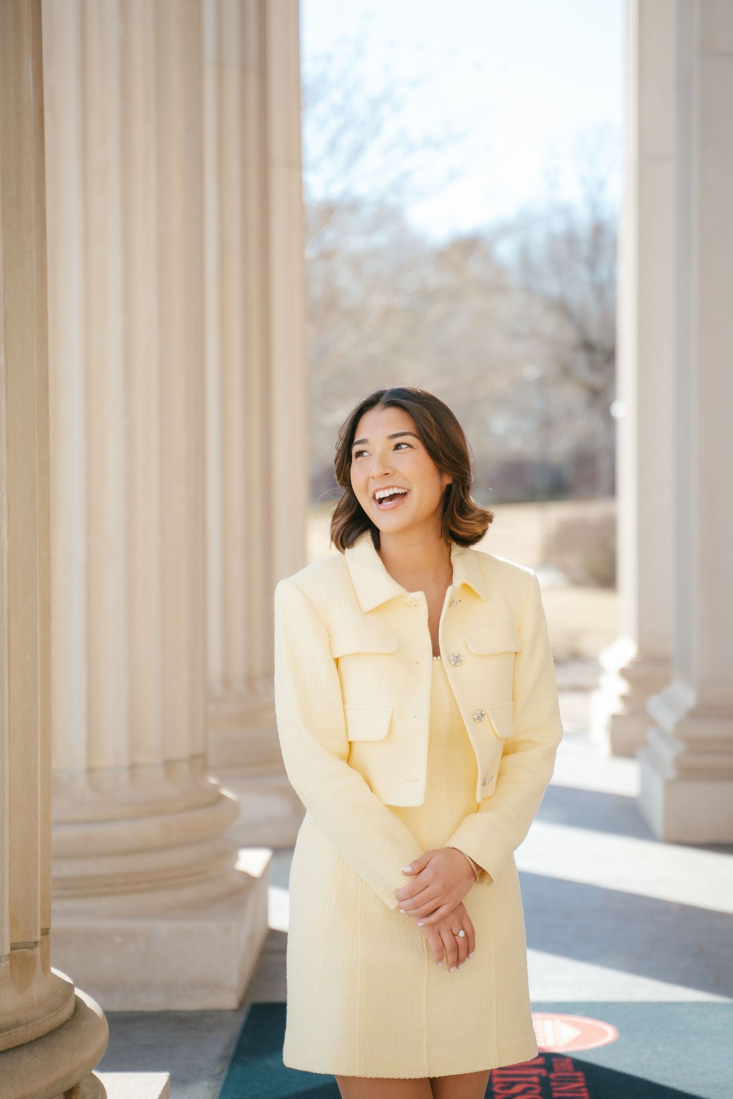 Portrait session featuring yellow ruffled top among classical white columns.