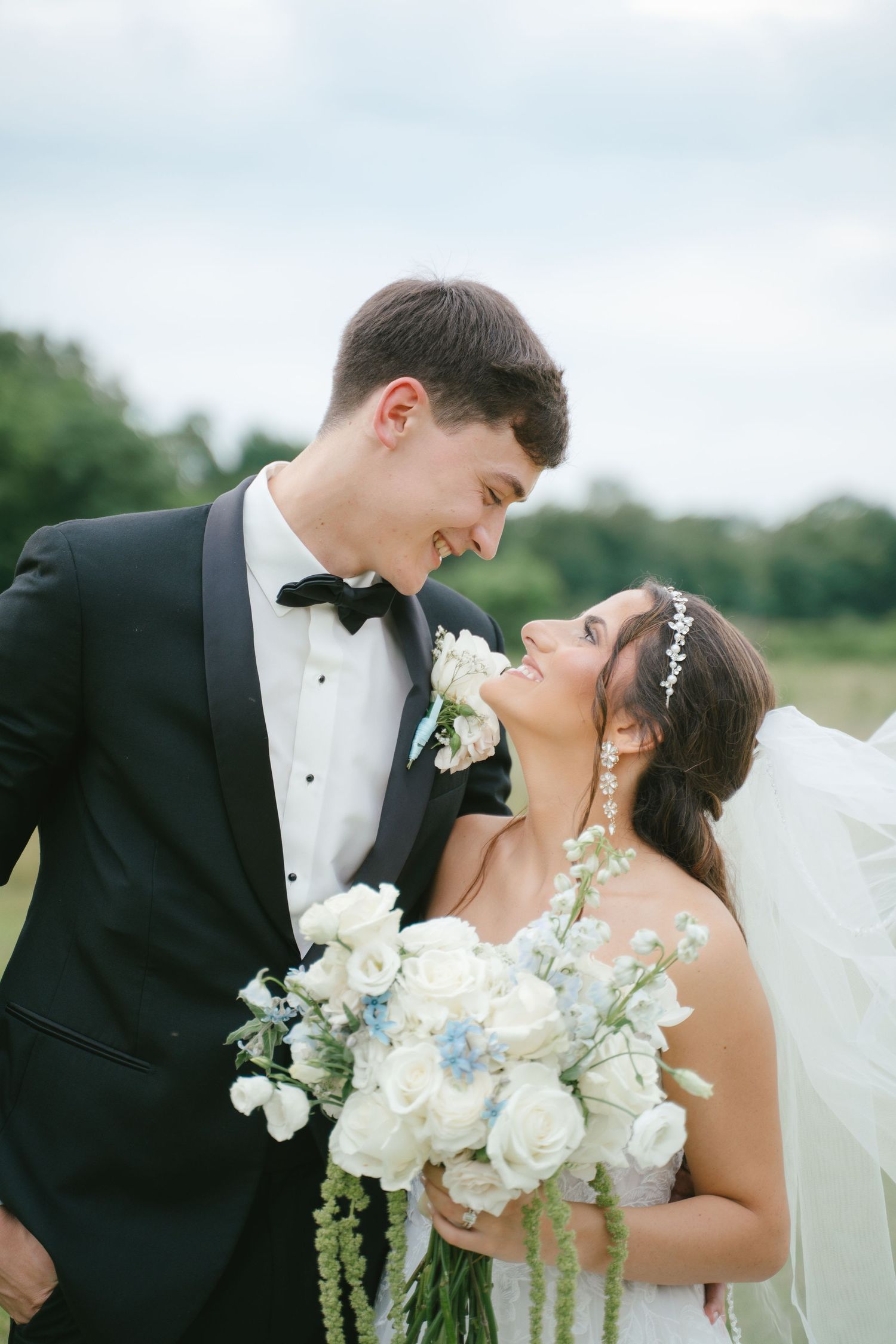 Romantic wedding portrait of couple embracing with white rose bouquet.