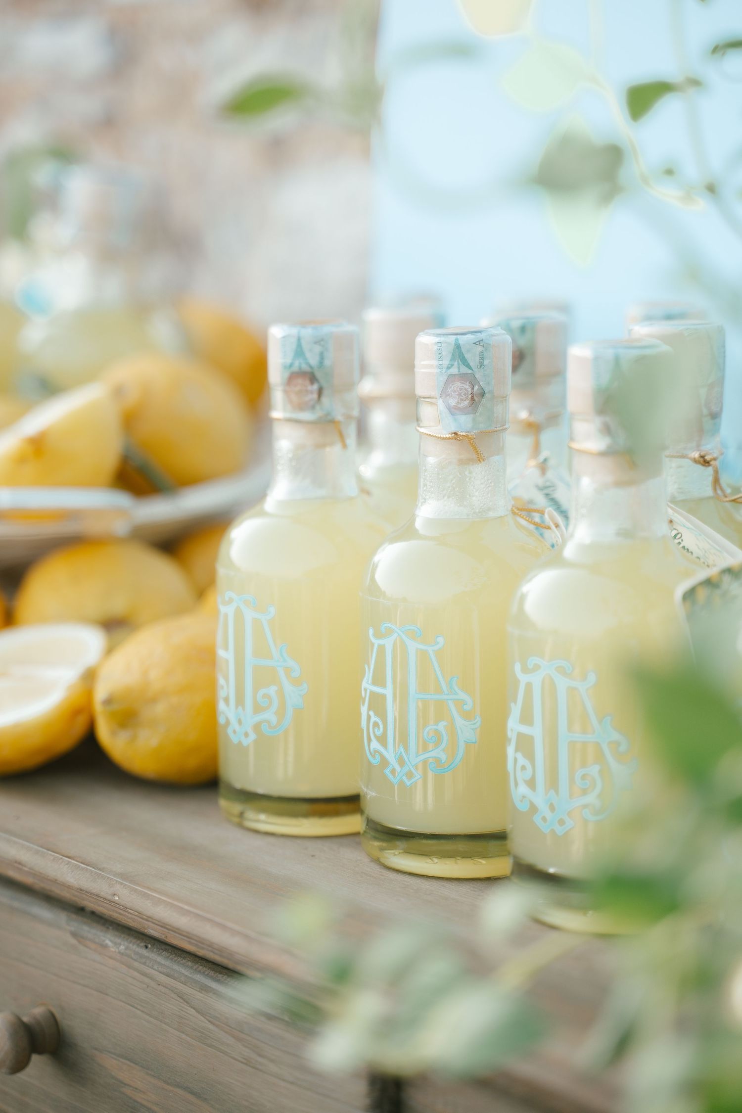 Row of glass bottles filled with fresh lemonade on wooden surface.