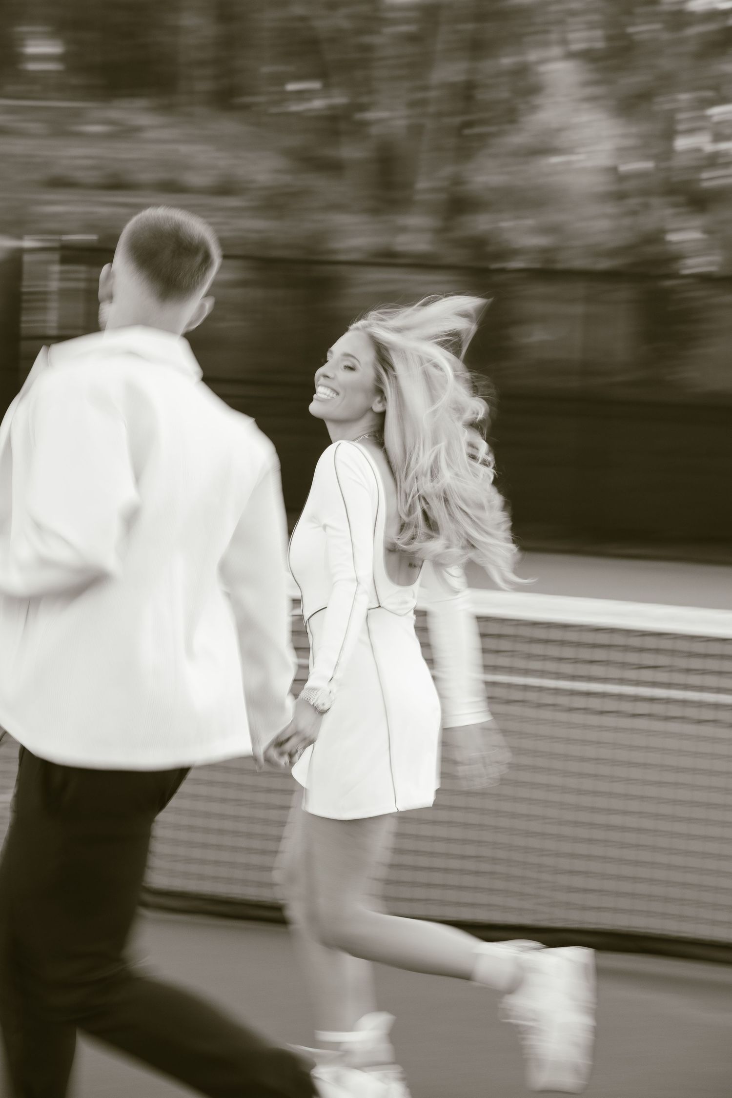 Black and white motion shot of couple dancing on tennis court.