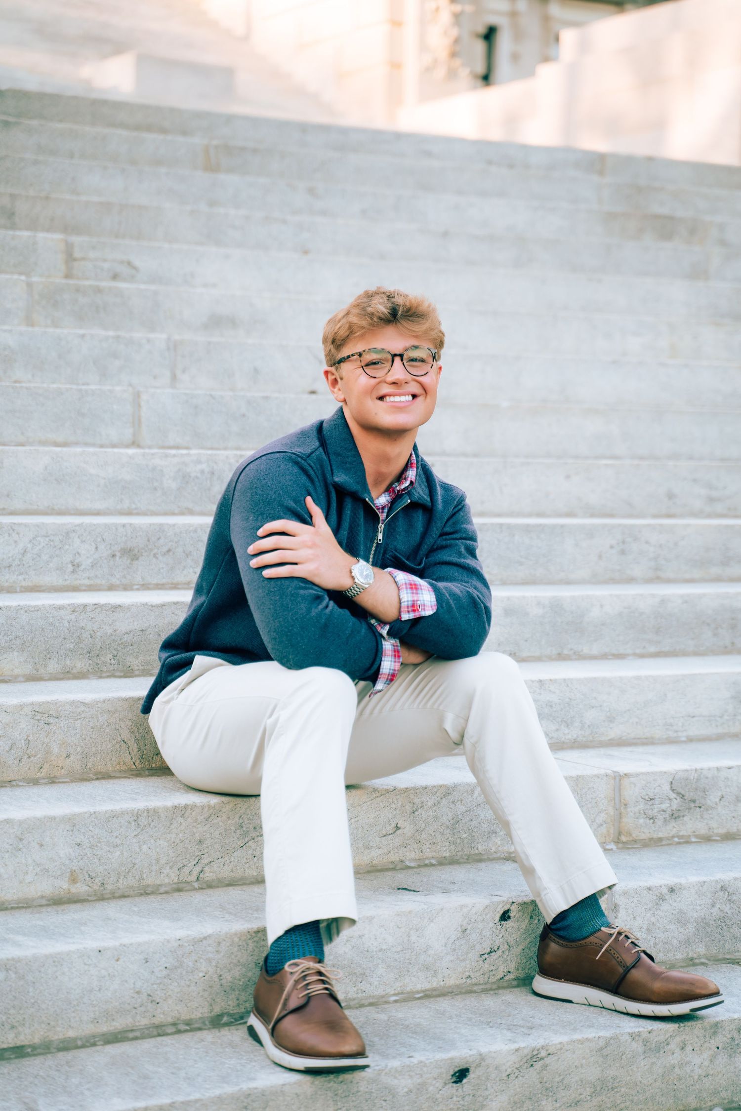 Person in casual attire sitting relaxed on concrete steps outdoors.
