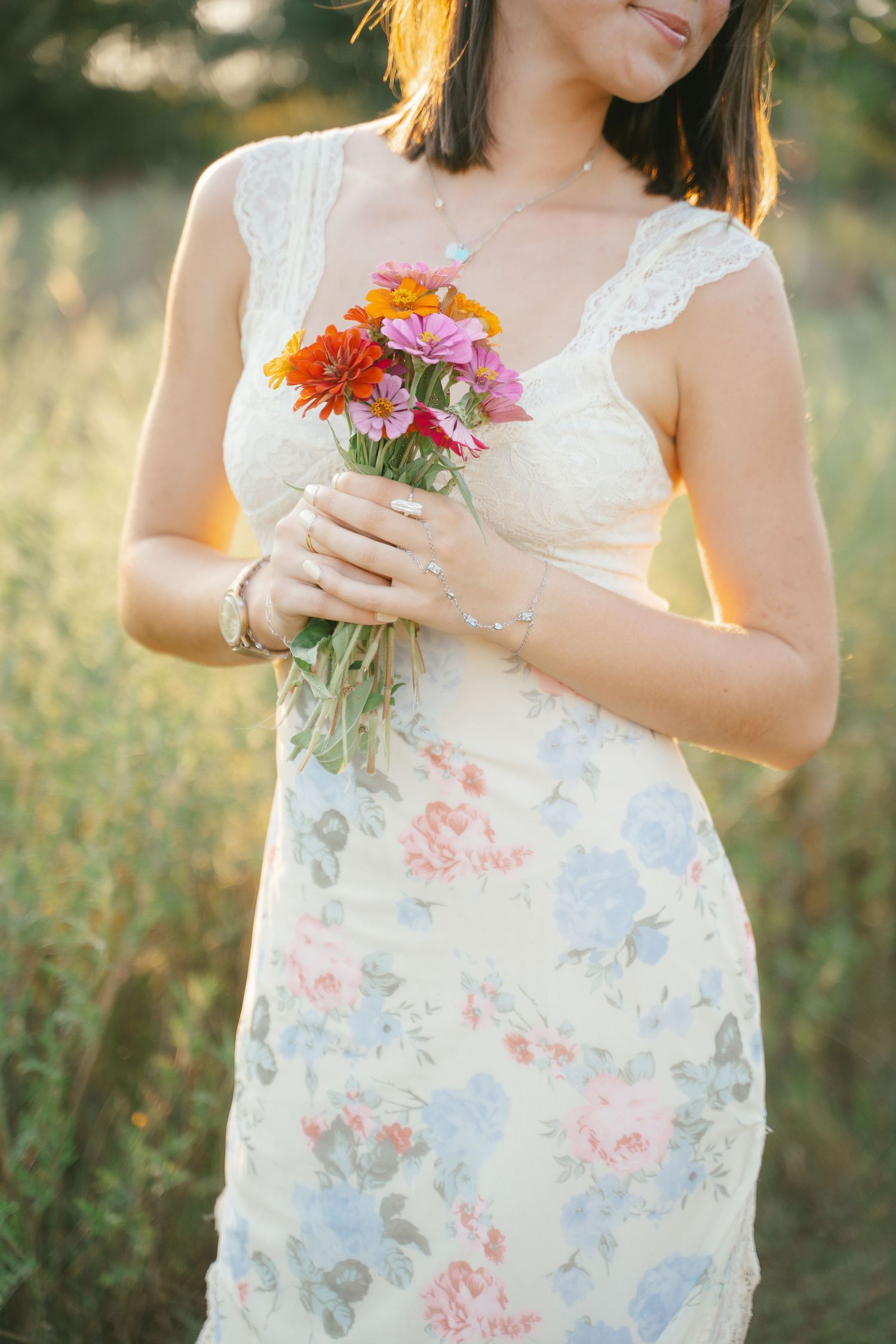 Close-up of floral dress and colorful wildflower bouquet in golden sunlight.