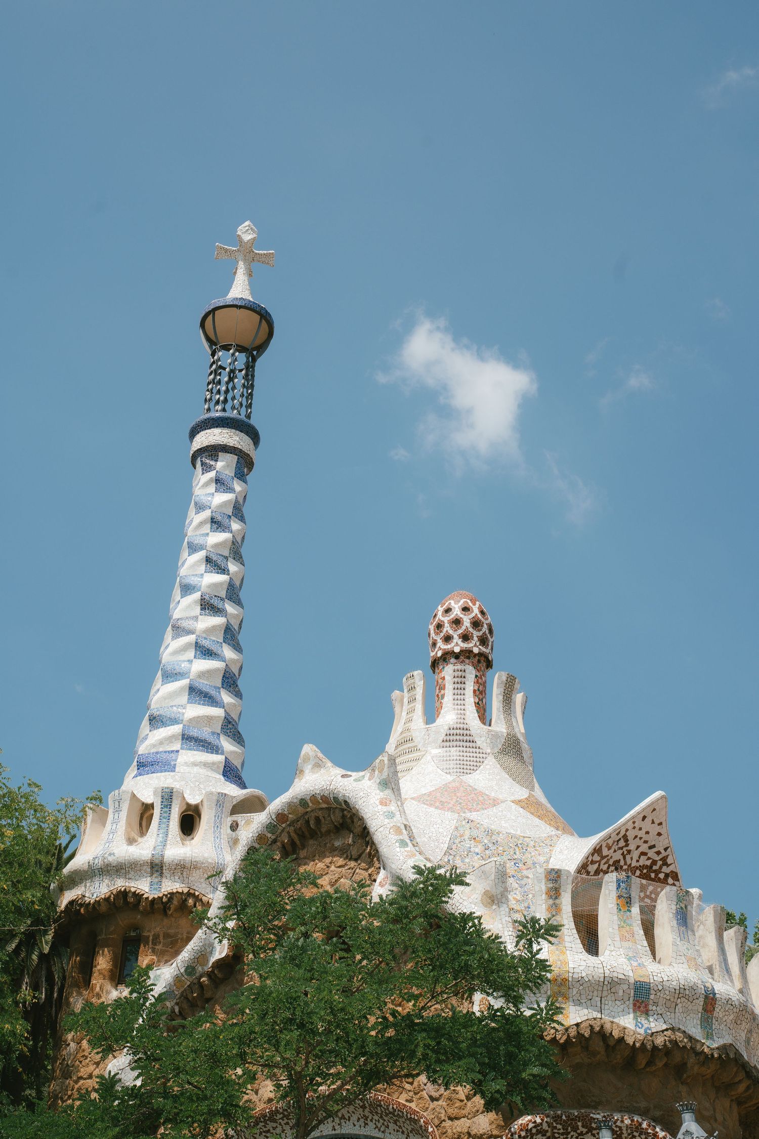 Architectural details of Park Guell in Barcelona showing Gaudi's distinctive white mosaic spires against a blue sky.