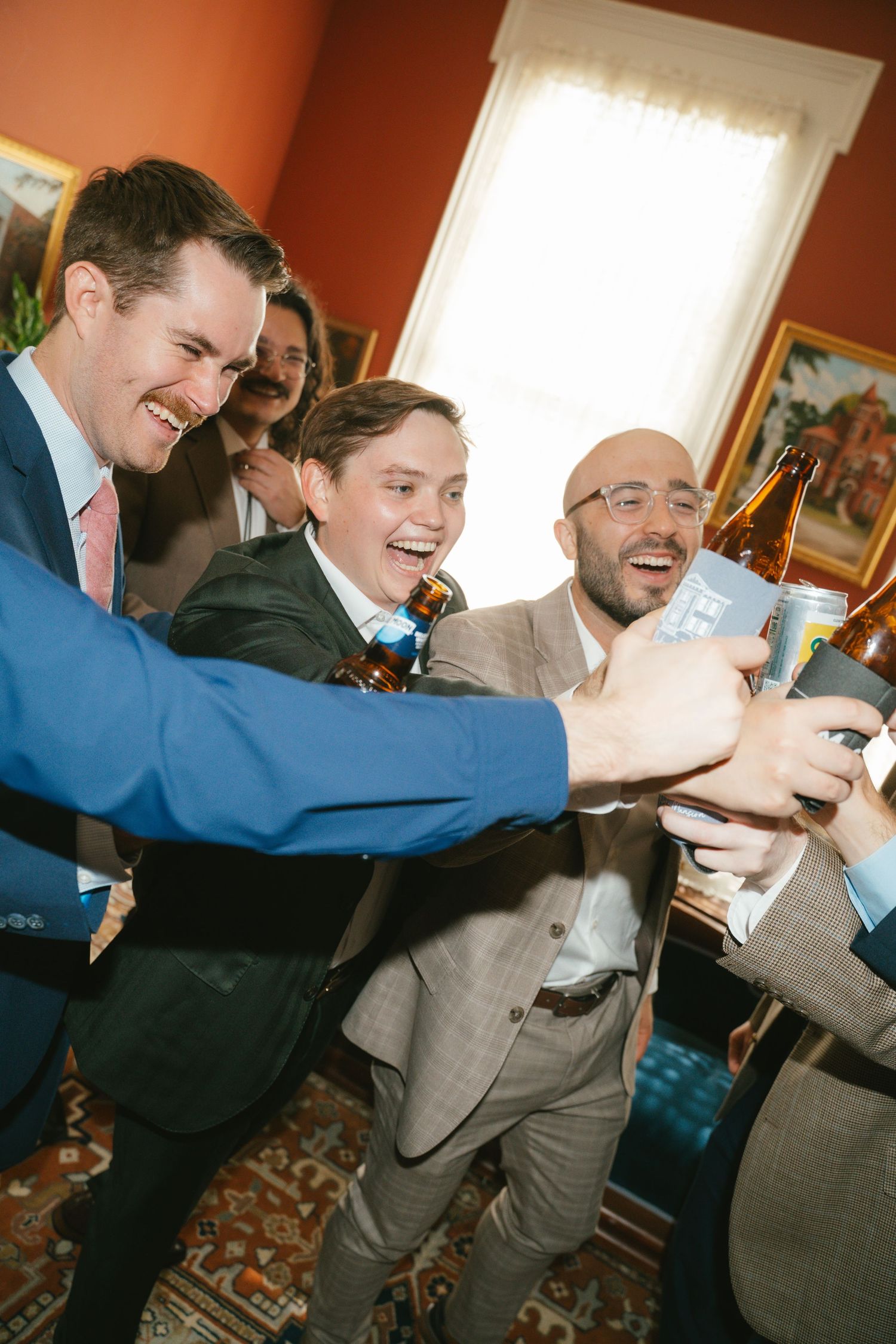 Groomsmen in suits playfully posing together during pre-wedding preparations.